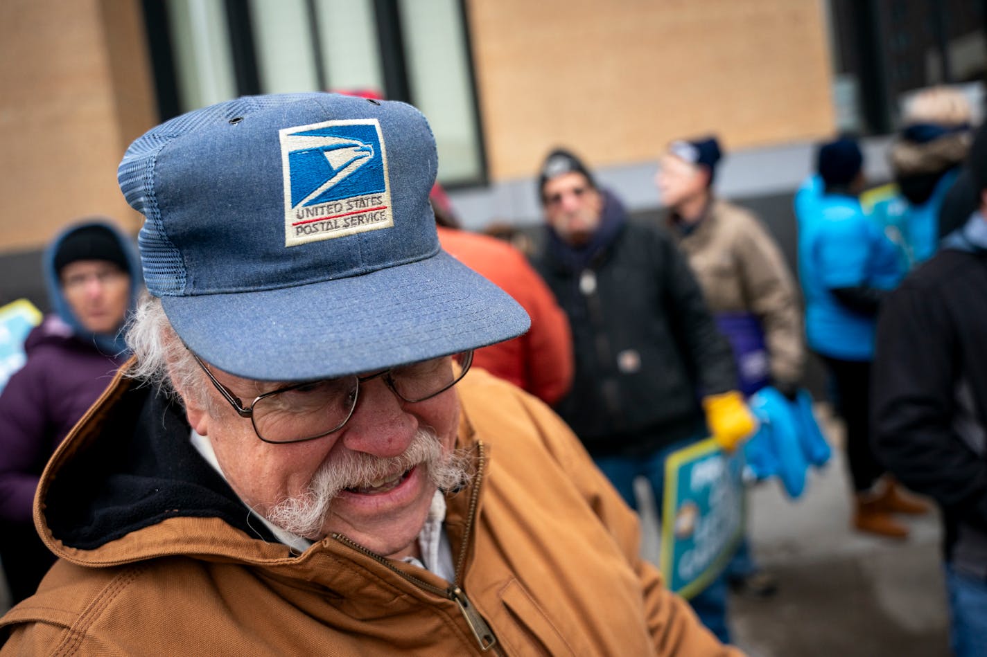 Tom Quinn, sporting a United States Postal Service hat, talks to other letter carriers, carrier union members and supporters as they rally with the National&nbsp;Association of Letter Carriers (NALC) outside the main United States Post Office in Minneapolis, Minn. on Sunday, Jan. 7, 2024. With rising rates in violence against letter carriers, the NALC is demanding better protection for city carriers and for the justice system to more adequately prosecute attackers. ] Angelina Katsanis • angelina.katsanis@startribune.com