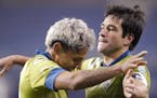 Seattle Sounders' Raul Ruidiaz, left, and Nicolas Lodeiro embrace after the team's 1-0 win over FC Dallas in an MLS playoff soccer match Tuesday, Dec.
