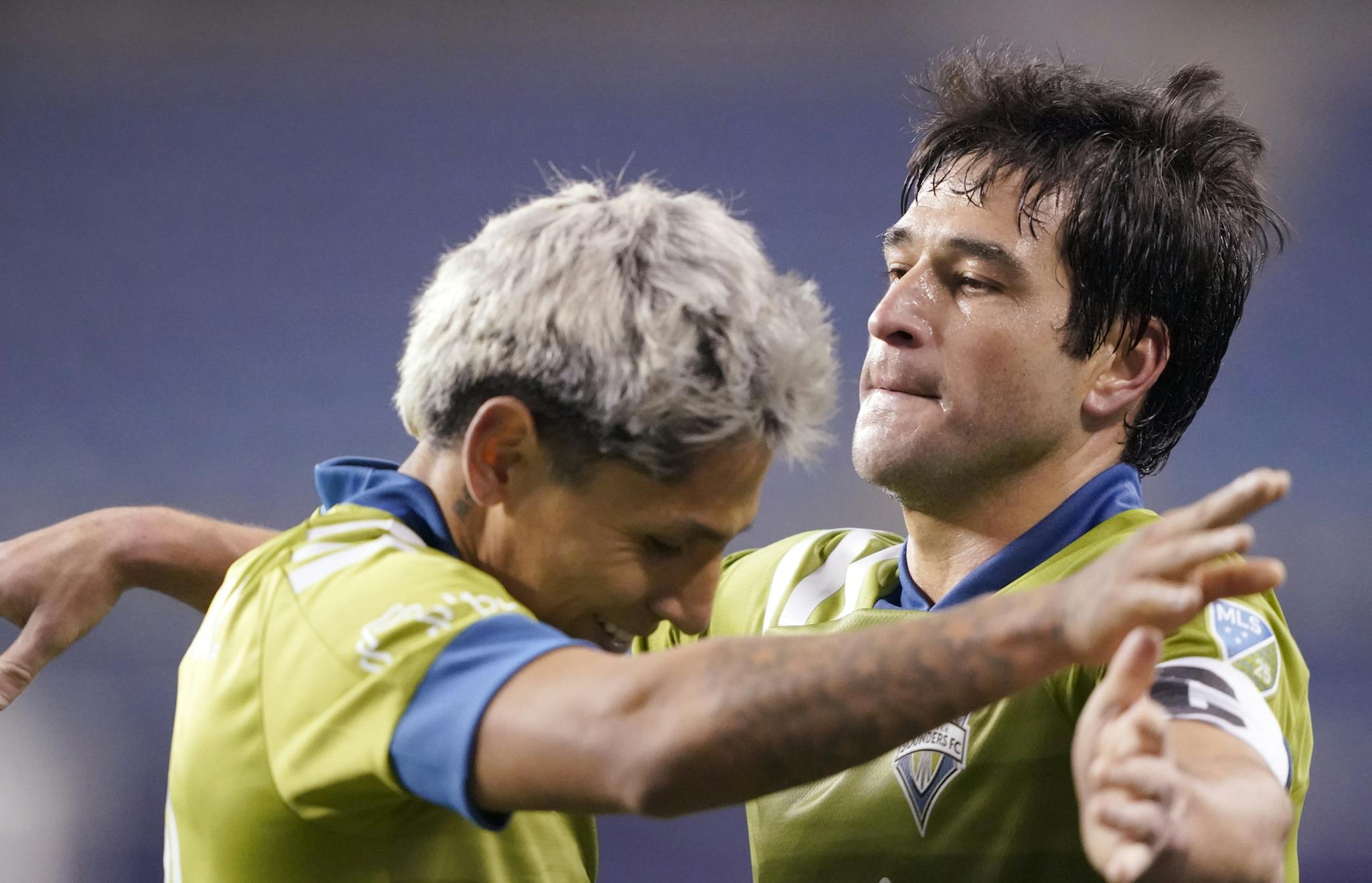 Seattle Sounders' Raul Ruidiaz, left, and Nicolas Lodeiro embrace after the team's 1-0 win over FC Dallas in an MLS playoff soccer match Tuesday, Dec. 1, 2020, in Seattle.