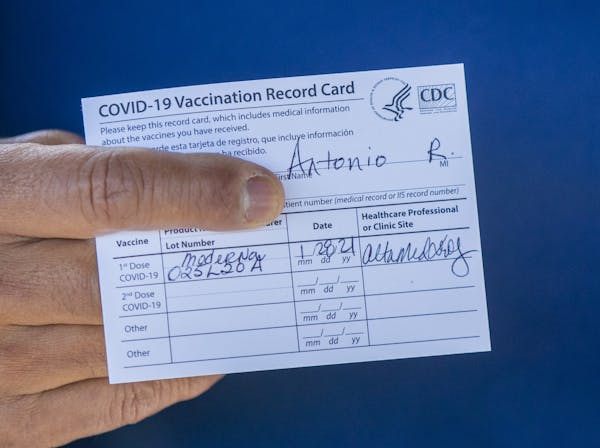 Former Los Angeles Mayor Antonio Villaraigosa holds his vaccination card after receiving his first shot of the Moderna COVID-19 vaccination in January