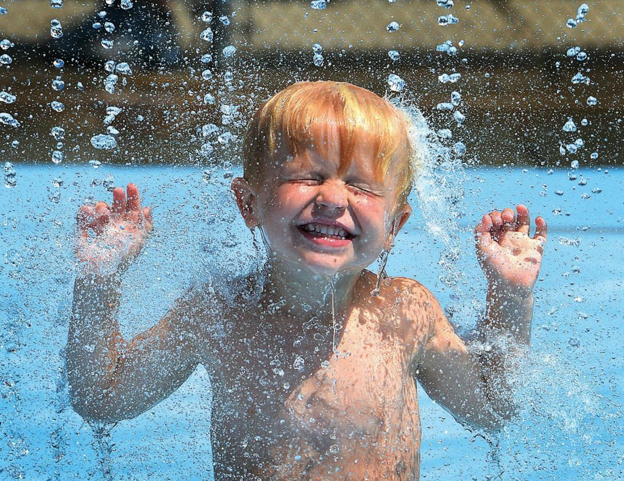 Philip Jeschke, 4, stays cool under the waterfall tower in the splash pool at The Wilton Family Y on Tuesday, July 16, 2013, in WIlton, Conn.. With temperatures near 100 degrees, the Y was one of the coolest places in town.