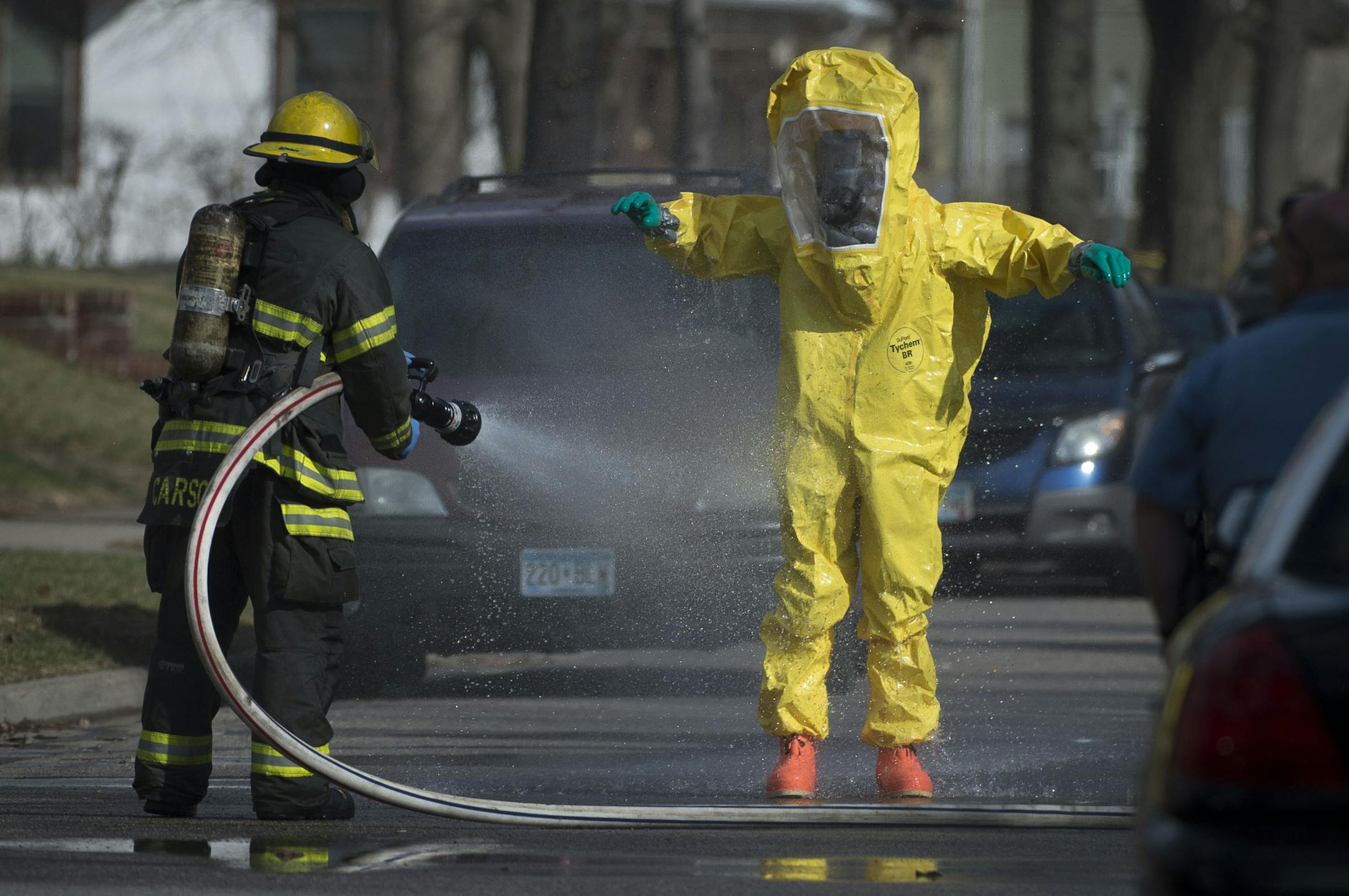A hazardous material worker is hosed down by a member of the Minneapolis Fire Department after leaving a residence in the Marcy Holmes neighborhood of Minneapolis on the 500 block of 6th Street Southeast on Friday, April 10, 2015. ] (Aaron Lavinsky | StarTribune)
