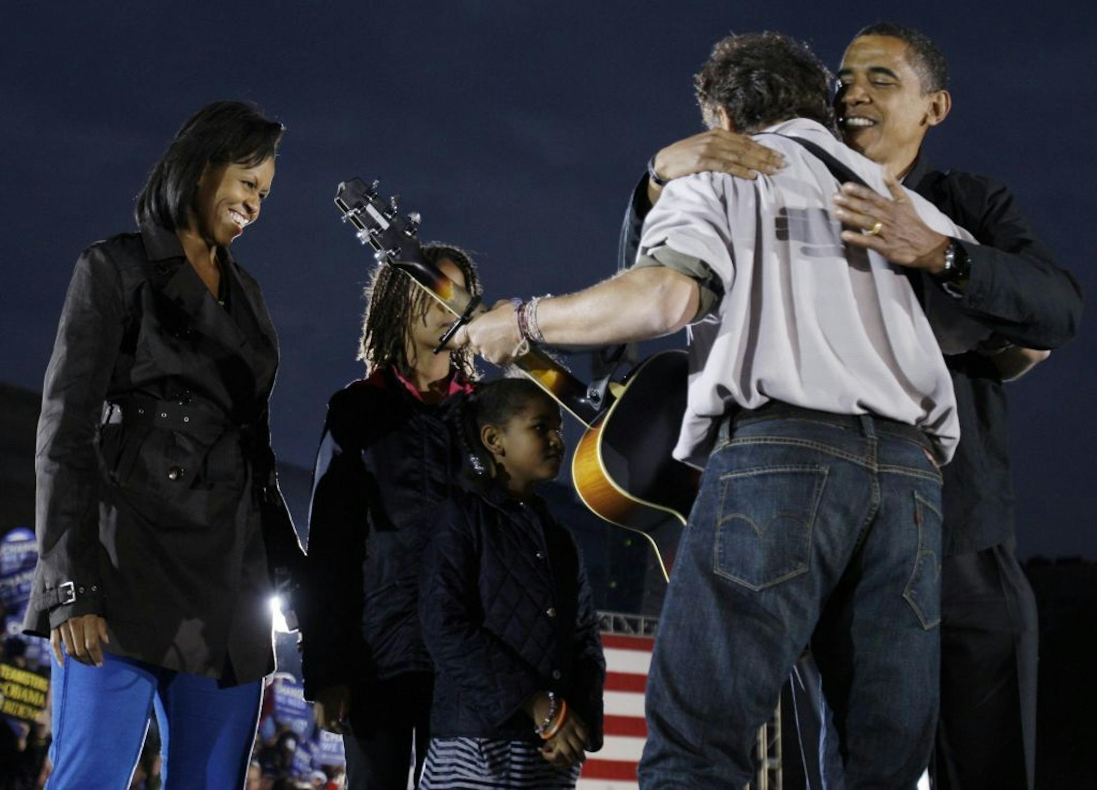 FILE - In this Nov. 2, 2008, file photo then-Democratic presidential candidate Barack Obama on stage with his wife Michelle Obama and daughters Malia and Sasha, hugs Bruce Springsteen at a rally at the Cleveland Mall, in Cleveland, Ohio.