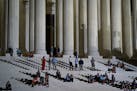 People sit and stand on the steps of the Supreme Court after President Donald Trump announced his nominee to the Supreme Court in Washington, July 9, 