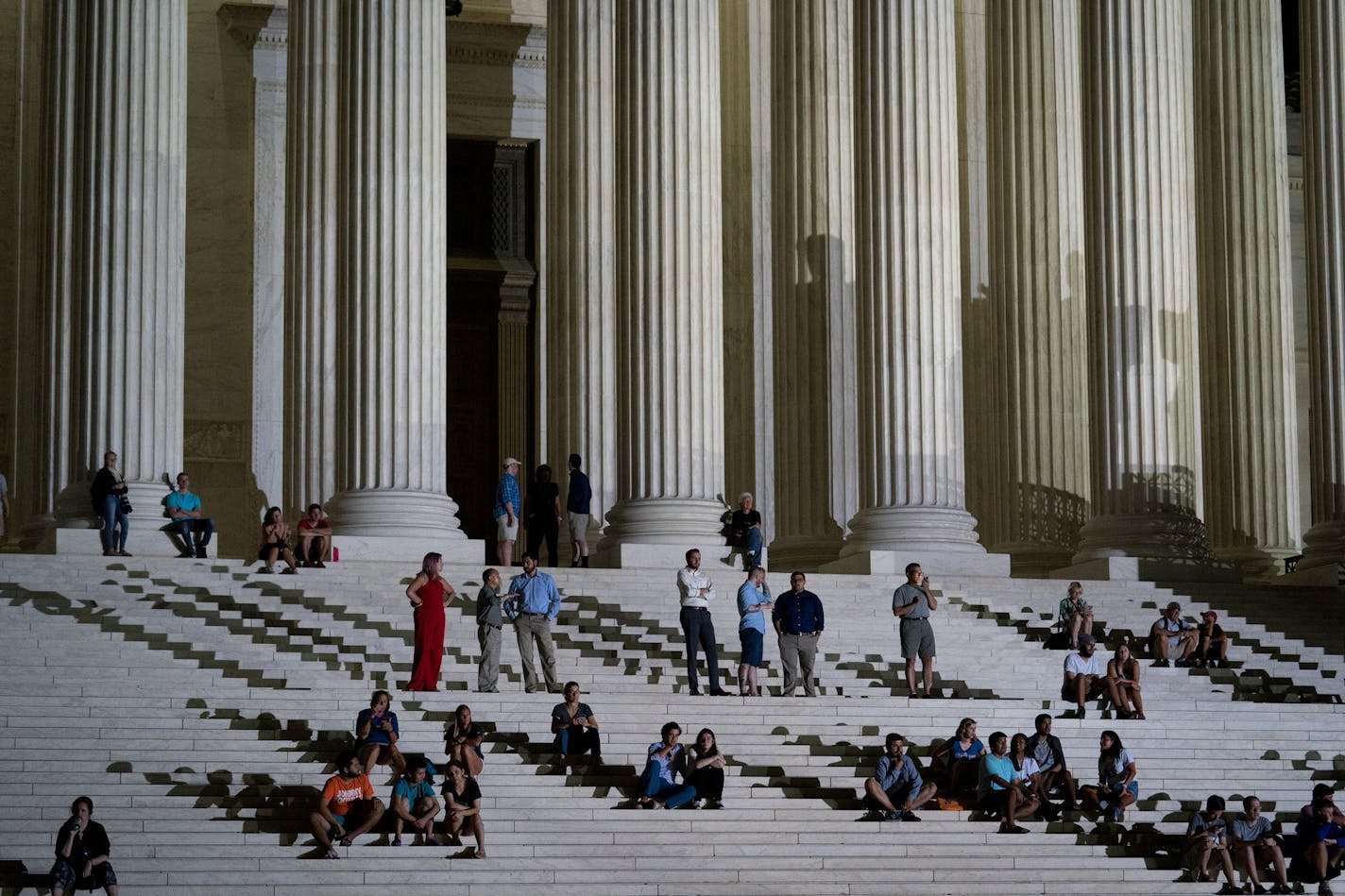 People sit and stand on the steps of the Supreme Court after President Donald Trump announced his nominee to the Supreme Court in Washington, July 9, 2018. Judge Brett Kavanaugh, President Trump&#xed;s new nominee, could help Republicans hold or expand control in the Senate, even as it helps Democrats&#xed; chances to take the House. (Erin Schaff/The New York Times)