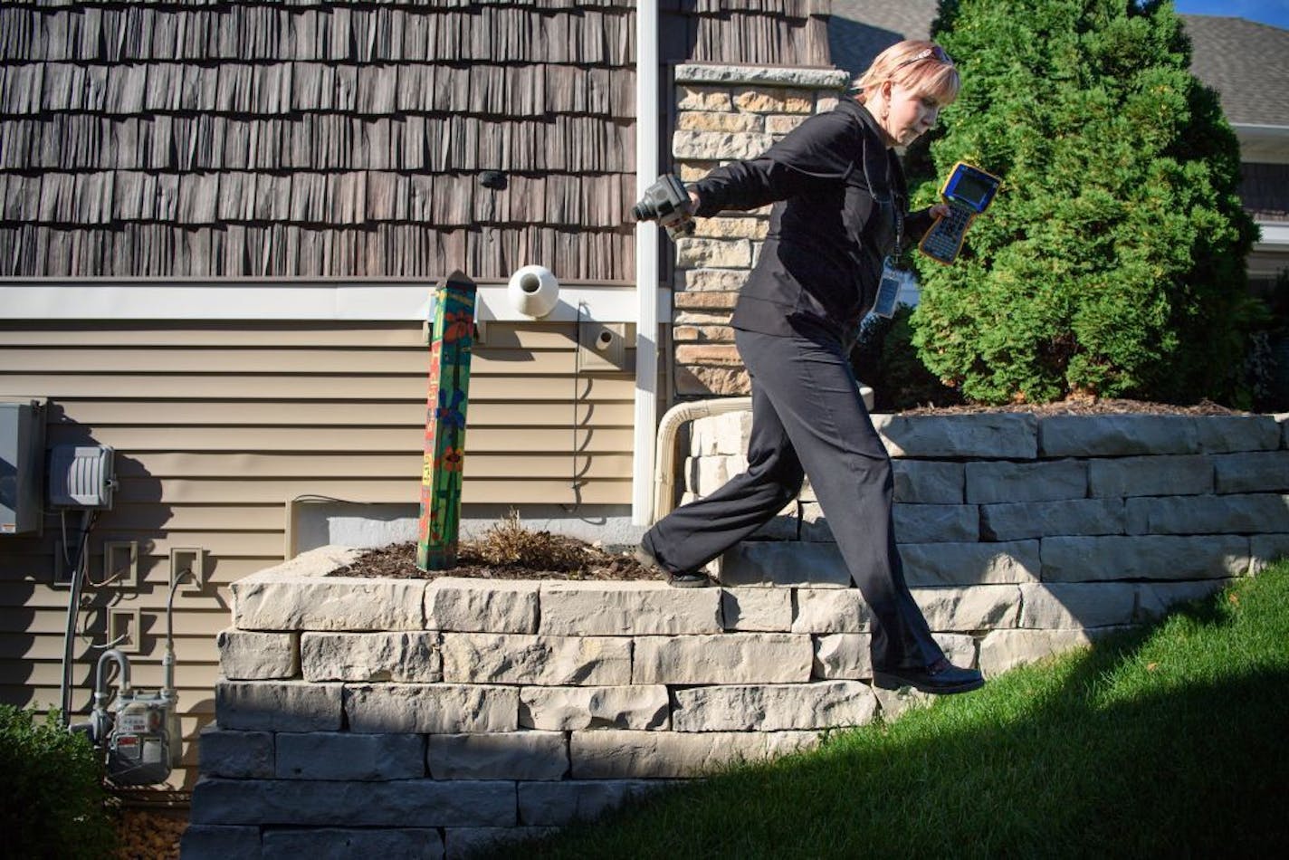 Jenny Rhoades, a public works meter reader for Bloomington walked briskly from house to house in a new Bloomington neighborhood capturing water readings from a sensor on the side of each house.