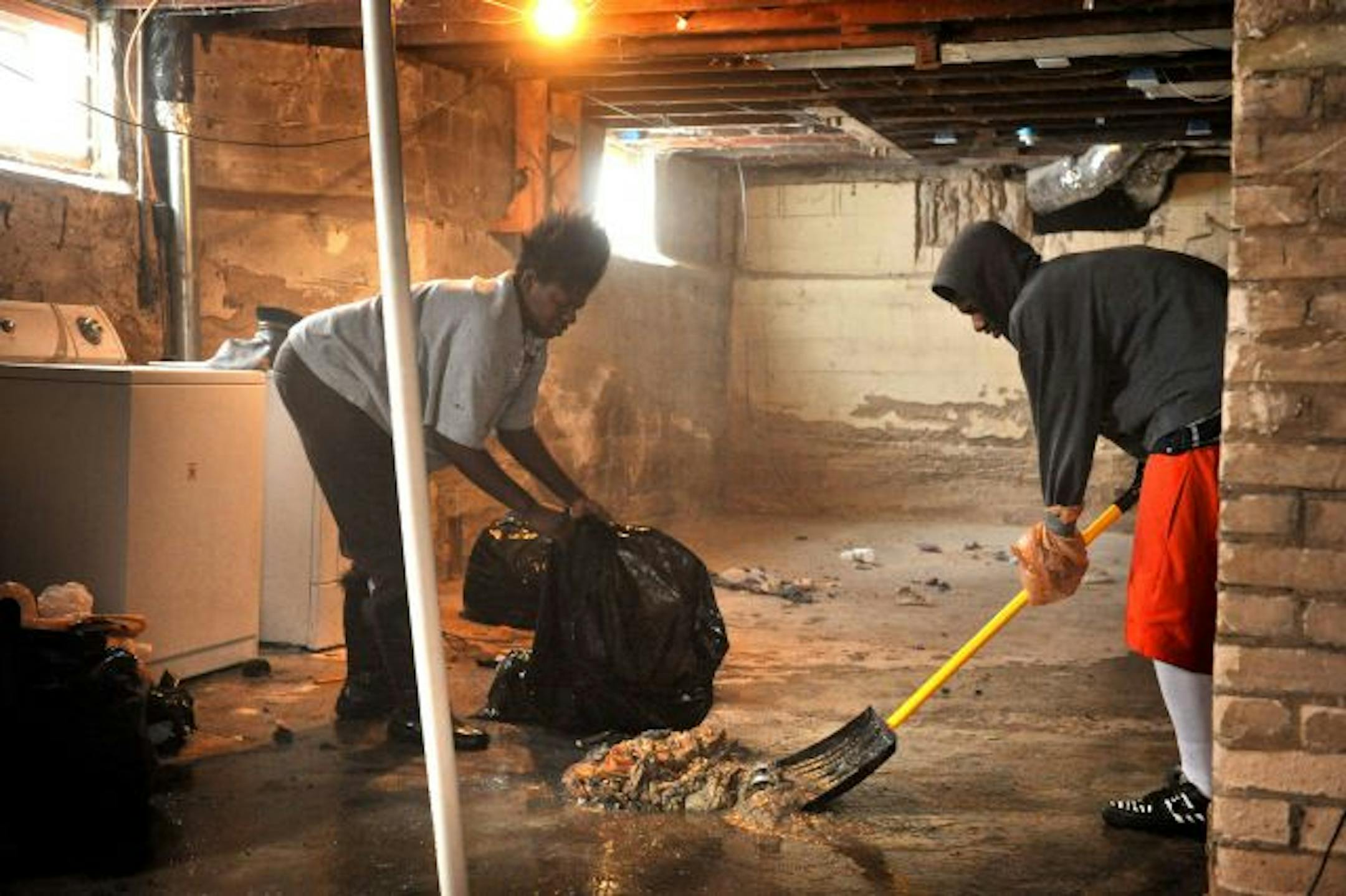 Rosie Lee and son Bobby, 15, worked to clean up sewage that had drained into the basement of the home they rent.