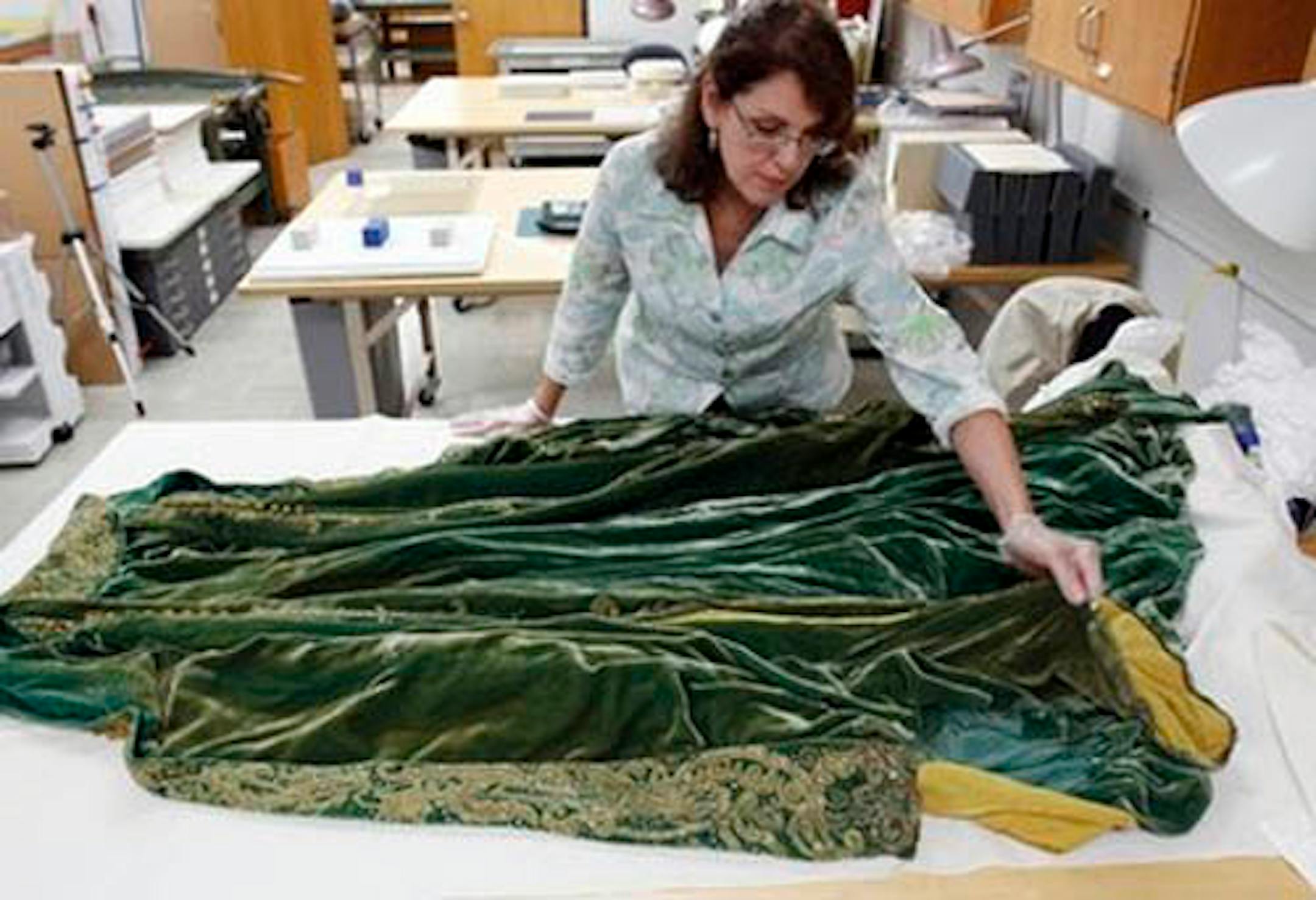 Cara Varnell, an independent art conservator who specializes in Hollywood film costumes, works with the green velvet gown from the film "Gone With the Wind," Tuesday, July 19, 2011, in Austin, Texas. The Harry Ransom Center at the University of Texas is working to preserve five of the dresses acquired with the collection of film producer David O. Selznick in the 1980s. (AP Photo/Eric Gay)