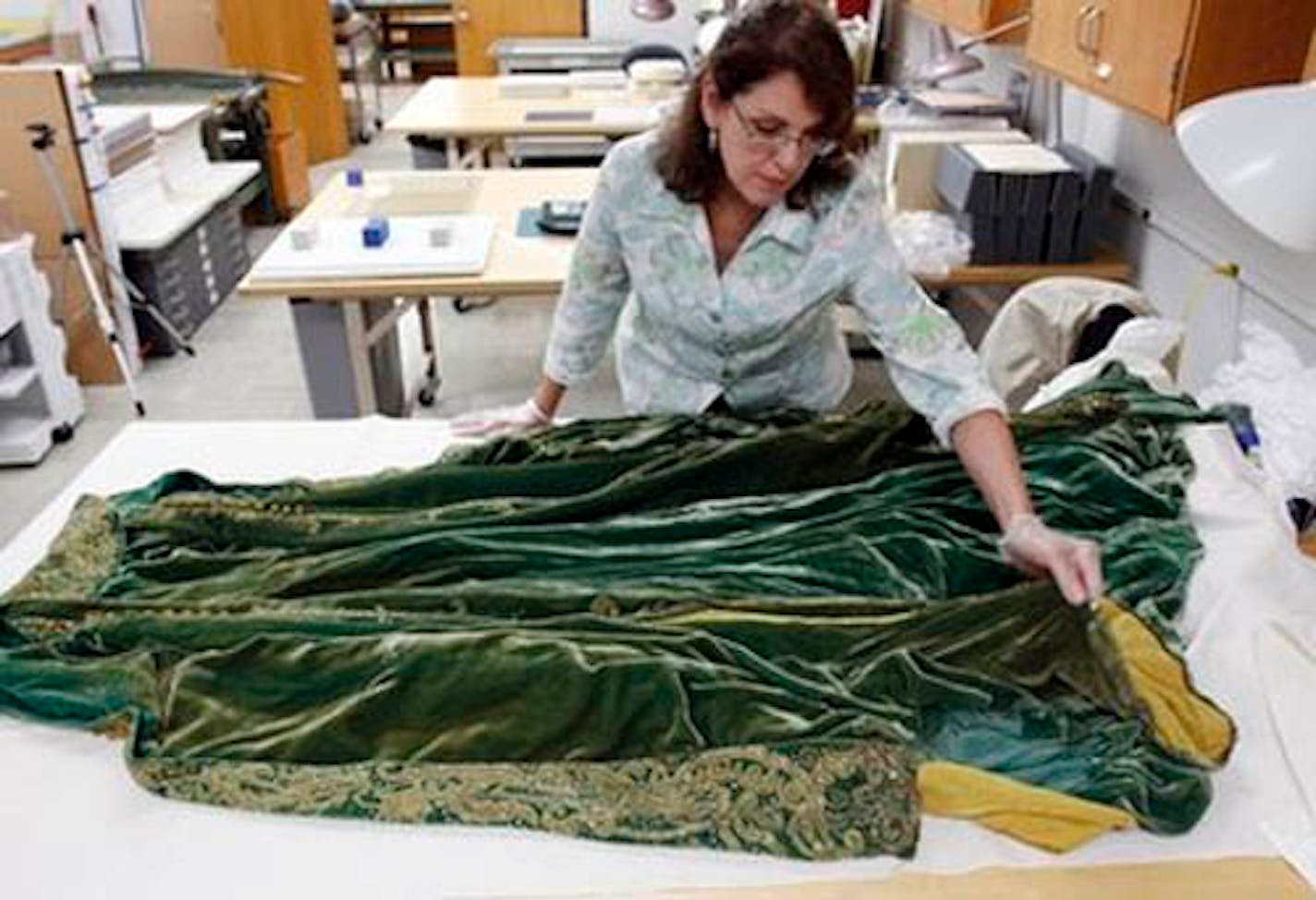 Cara Varnell, an independent art conservator who specializes in Hollywood film costumes, works with the green velvet gown from the film "Gone With the Wind," Tuesday, July 19, 2011, in Austin, Texas. The Harry Ransom Center at the University of Texas is working to preserve five of the dresses acquired with the collection of film producer David O. Selznick in the 1980s.  (AP Photo/Eric Gay)