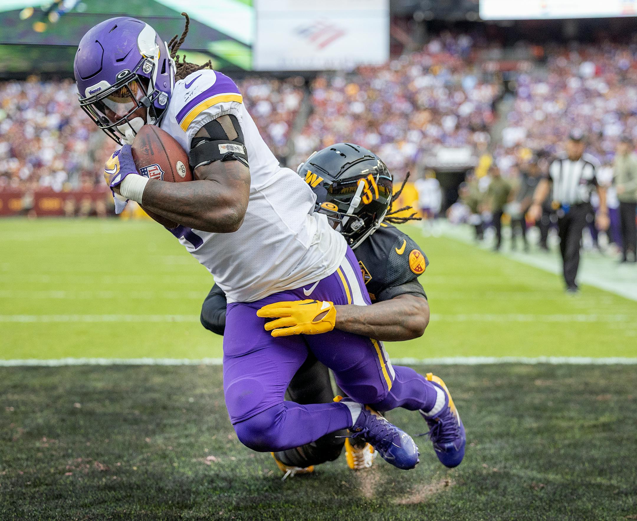 Minnesota Vikings running back Dalvin Cook (4) makes a one-handed grab in the back of the end zone for a touchdown defended by Washington Commanders safety Kamren Curl (31) in the fourth quarter.