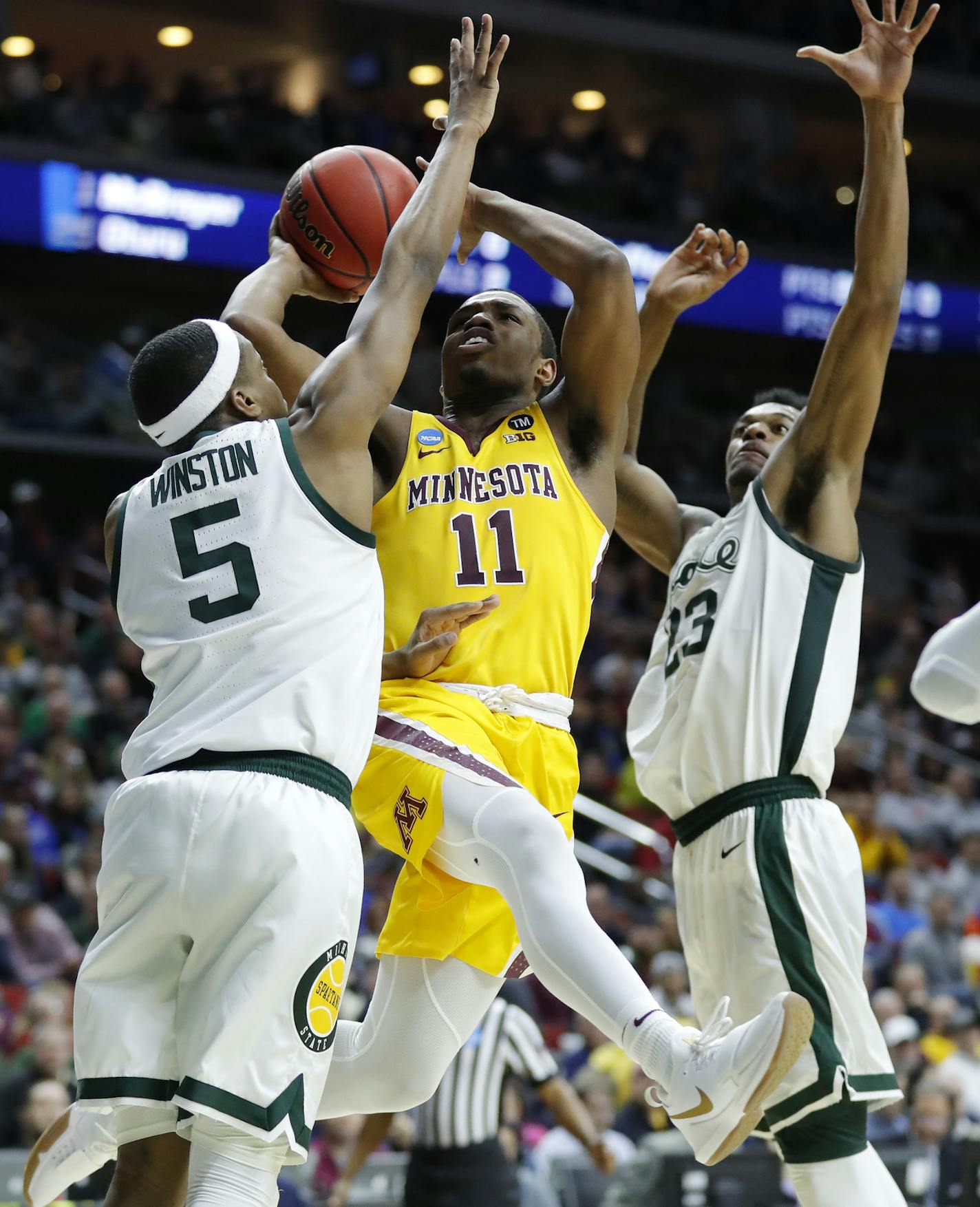 Minnesota guard Isaiah Washington (11) drives to the basket between Michigan State's Cassius Winston, left, and Xavier Tillman, right, during a second round men's college basketball game in the NCAA Tournament, Saturday, March 23, 2019, in Des Moines, Iowa. (AP Photo/Charlie Neibergall)