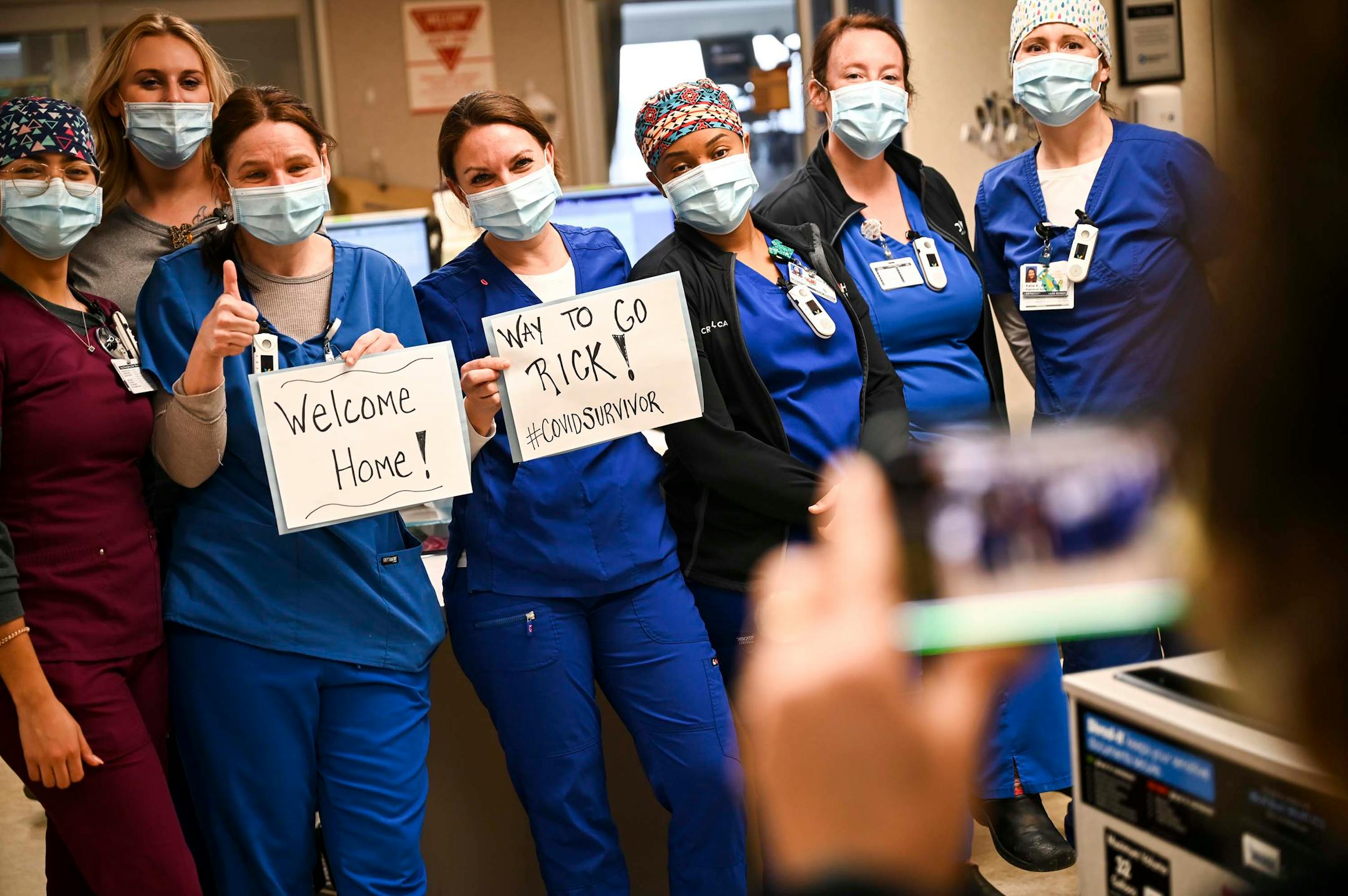 In 2021, Holly Vilione, center, took a photo with fellow critical care nurses in South Seven after they made signs celebrating the return home of a former patient of theirs, Rick Ulrich, who spent nearly a month in their care.