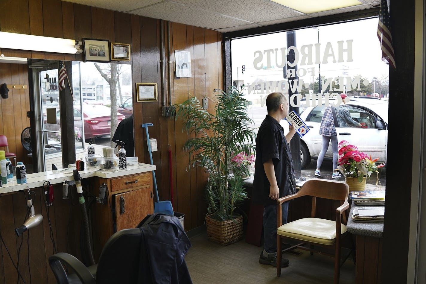 Mike Stevenson flipped his barber shop sign to closed after learning state regulators had clarified that hair and nail salons, spas and other similar businesses are included in Minnesota Gov. Tim Walz's order to cease operations Wednesday, March 18, 2020 in Columbia Heights, Minn. (Anthony Souffle/Star Tribune via AP)