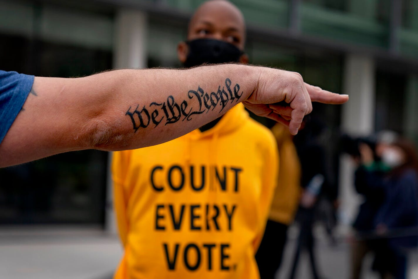 The tattoo "We the People," a phrase from the U.S. Constitution, decorates the arm of Trump supporter Bob Lewis as he argues with counterprotestor Ralph Gaines outside the central counting board at the TCF Center in Detroit, Thursday, Nov. 5, 2020.