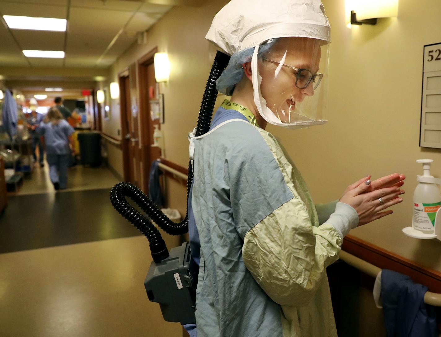 After donning personal protective equipment, registered nurse Sarah Neva sanitizes her hands before going in to check on a COVID-19 patient at Bethesda Hospital earlier in May.