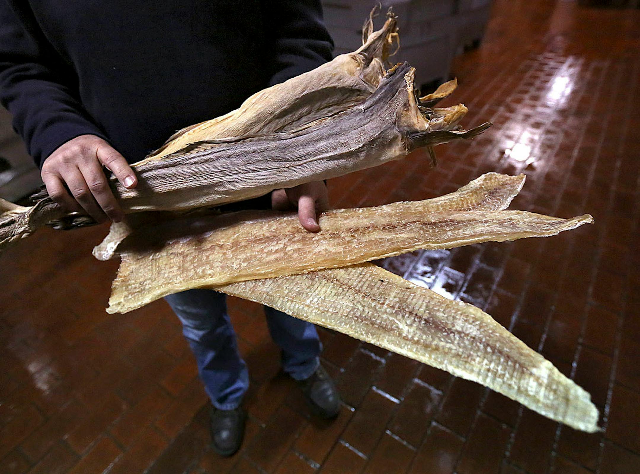 Chris Dorff, president of Olsen Fish Company, displayed some of the dried cod fillets used in the process to make lutefisk (bottom). Displayed on top, are full dried cod fish that are still sold, but no longer used to make lutefisk. ] JIM GEHRZ • james.gehrz@startribune.com / Minneapolis, MN / December 12 2014 /10:00 AM - BACKGROUND INFORMATION: Olsen Fish Company of Minneapolis is the largest maker of lutefisk in North America. Chris Dorff is president of the company.