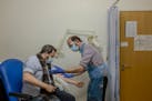 A volunteer at the at the Centre for Clinical Vaccinology and Tropical Medicine in Oxford, England, is prepared for a vaccine booster during the Oxfor