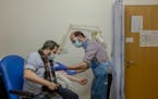 A volunteer at the at the Centre for Clinical Vaccinology and Tropical Medicine in Oxford, England, is prepared for a vaccine booster during the Oxfor