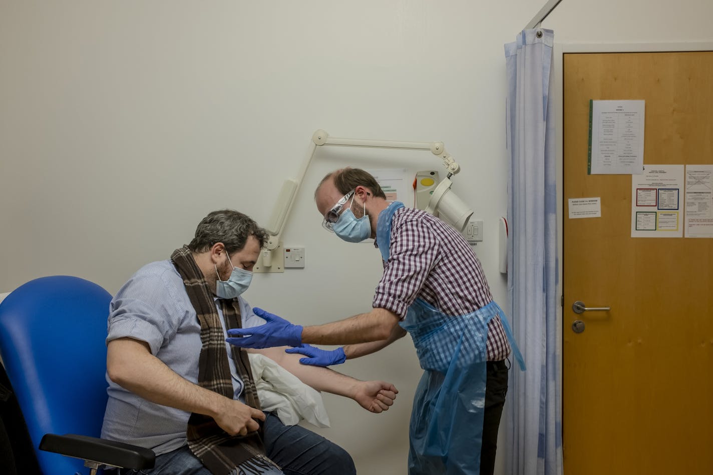 A volunteer at the at the Centre for Clinical Vaccinology and Tropical Medicine in Oxford, England, is prepared for a vaccine booster during the Oxford Vaccine Group's COVID-19 vaccine trials on Nov. 20, 2020.