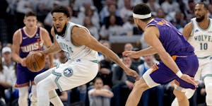 Karl-Anthony Towns of the is defended by Devin Booker of the Suns on Tuesday night at Target Center.