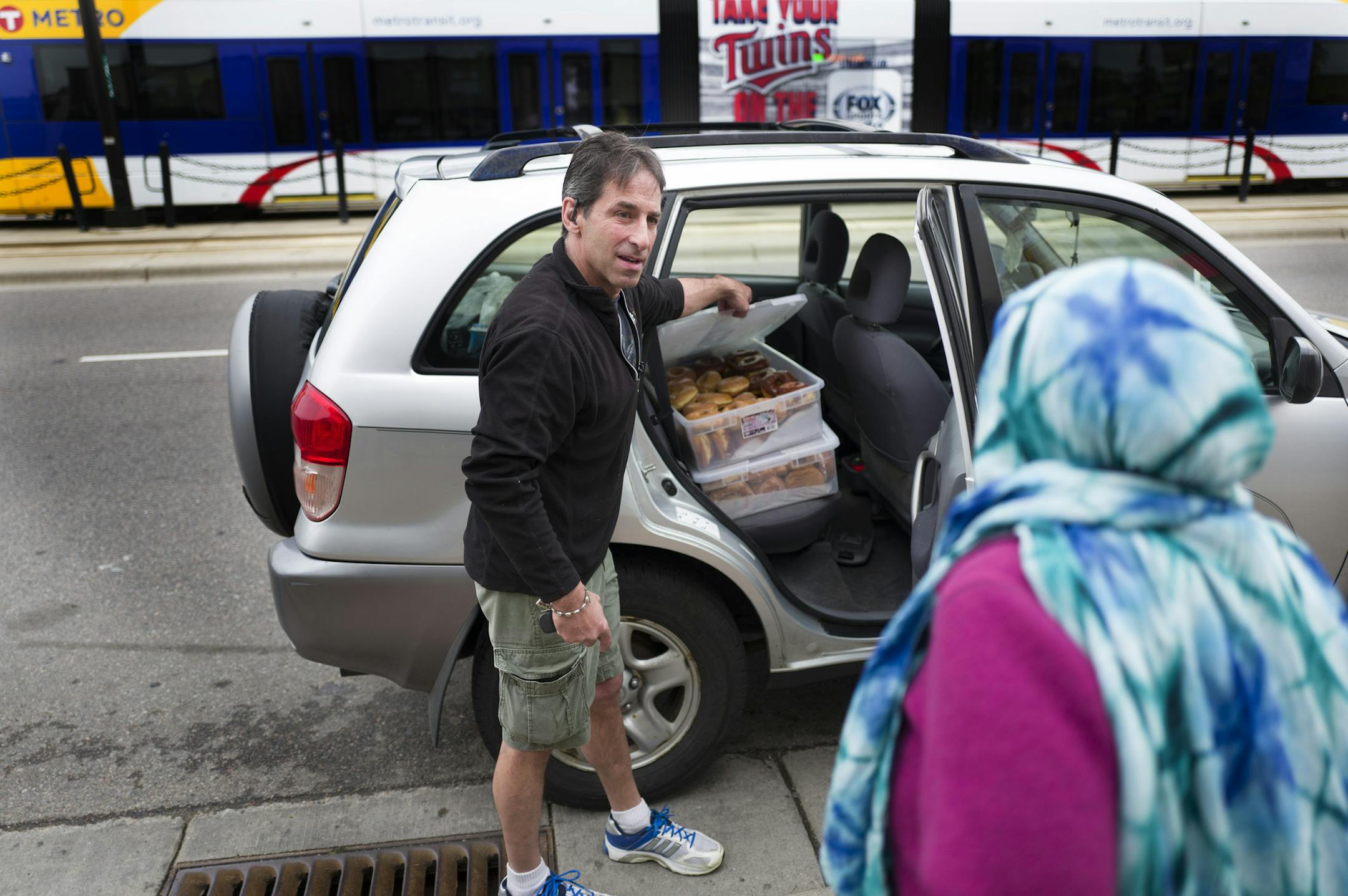 Chris Engelmann offered a fresh donut to a lady on University Avenue Tuesday in front of the SugaRush bakery May 10, 2016 in St. Paul, MN.] Chris Engelmann loaded donuts from the SugaRush bakery that he gives to homeless shelters, hospices, street people and even late-night concertgoers. Jerry Holt /Jerry.Holt@Startribune.com