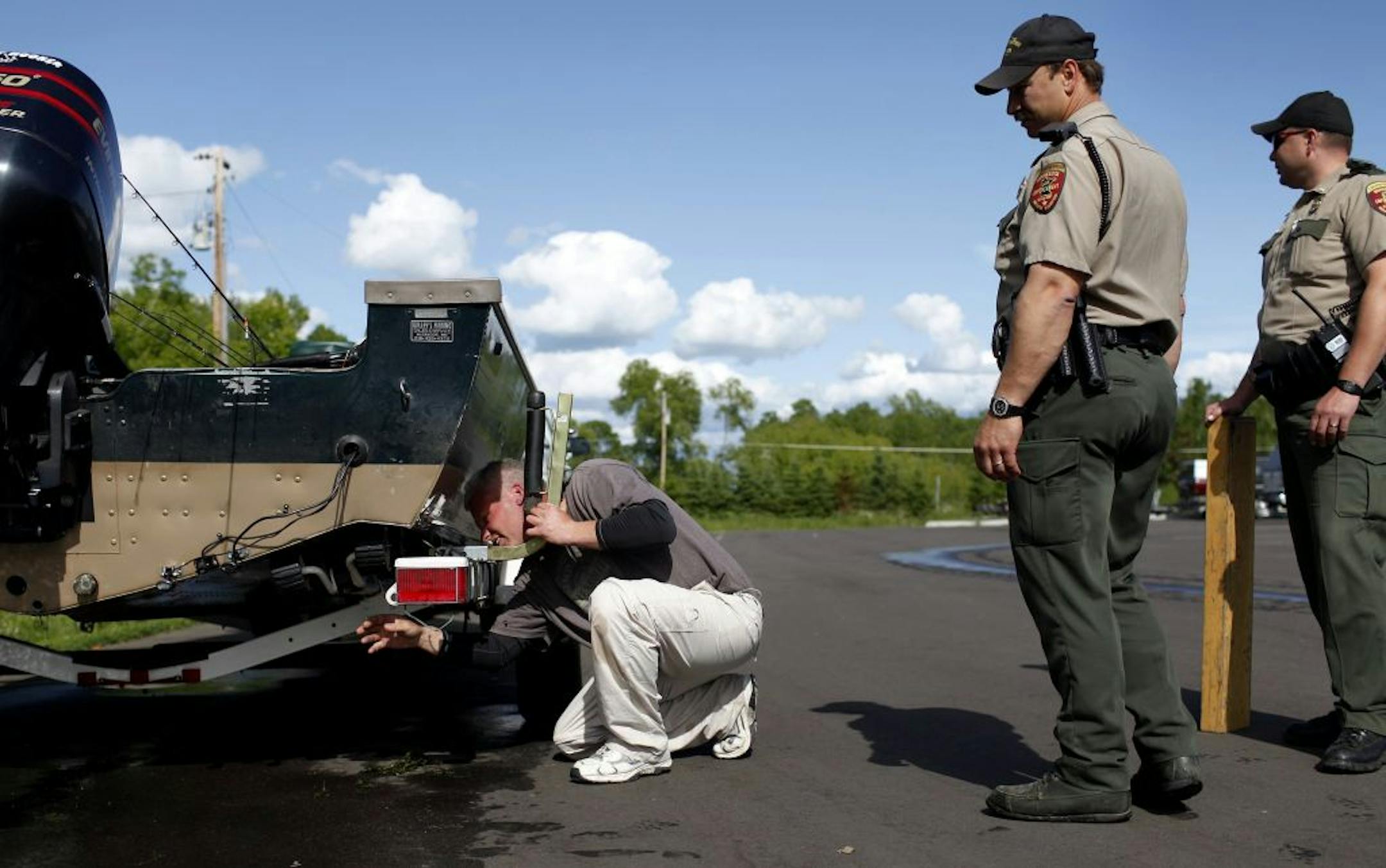 FILE -- DNR conservation officers Luke Croatt, left and Scott Fitzgerald inspected a boat on a ramp at Mille Lacs Lake, looking for invasive species, in July 2012.
