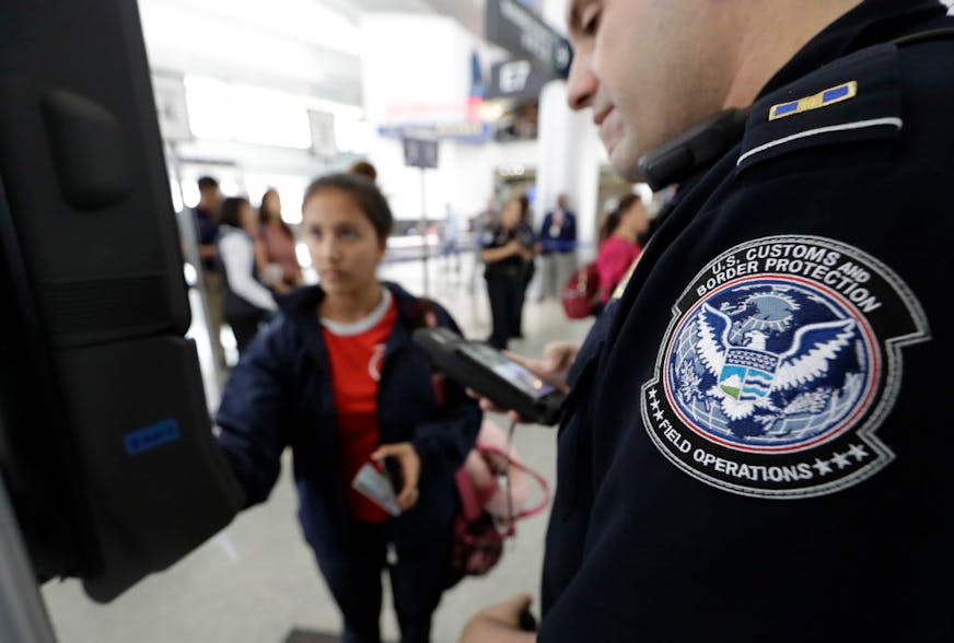 U.S. Customs and Border Protection officer Julio Corro, right, helps a passenger navigate one of the new facial recognition kiosks at a United Airlines gate before boarding a flight to Tokyo, Wednesday, July 12, 2017, at George Bush Intercontinental Airport, in Houston. The Trump administration intends to require that American citizens boarding international flights submit to face scans, something Congress has not explicitly approved and privacy advocates consider an ill-advised step toward a su