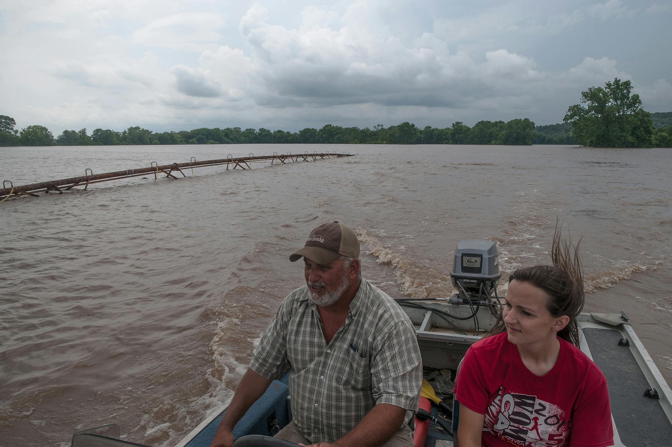 Chris Schaefers, left, and his neighbor and fellow farmer, Jill Edwards, pass an irrigation system nearly covered by floodwaters in swamped crop fields in Faulkner County, Ark., June 5, 2019. Fast currents and swollen channels have rendered many rivers unsafe for commercial traffic, spreading economic pain from a spring of severe floods.