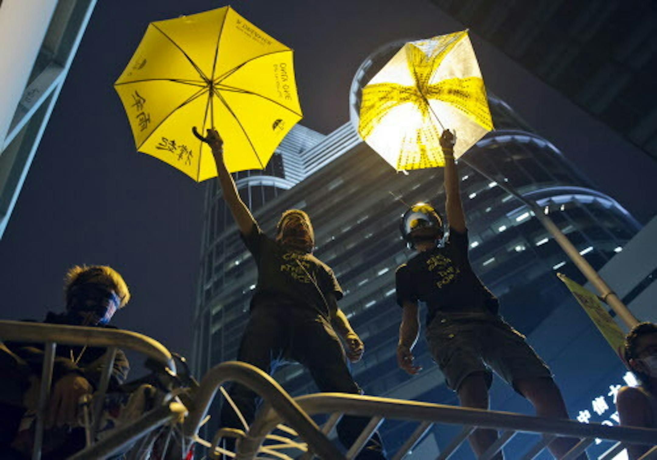 In this Wednesday, Dec. 10, 2014 photo, protesters lift yellow umbrellas, the symbol of pro-democracy movement in Hong Kong, on a barricade as the police's advancement to clear their barricades and tents is imminent at the occupied area outside government headquarters in Hong Kong. Hong Kong's dwindling number of pro-democracy protesters vowed Wednesday to stay until the last minute before authorities clear them off a highway where they've been camped out for more than two months. (AP Photo/Kin