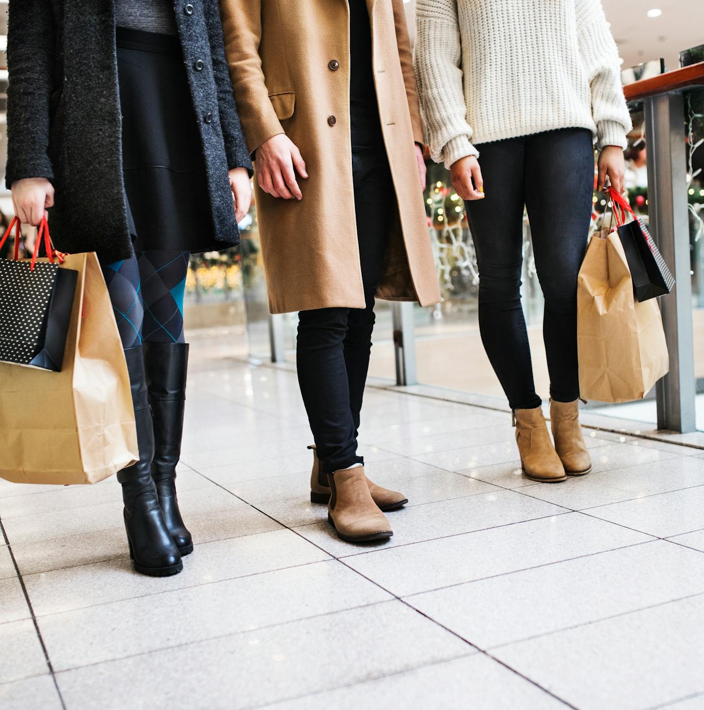 Unrecognizable young friends with bags walking in shopping center at Christmas time.