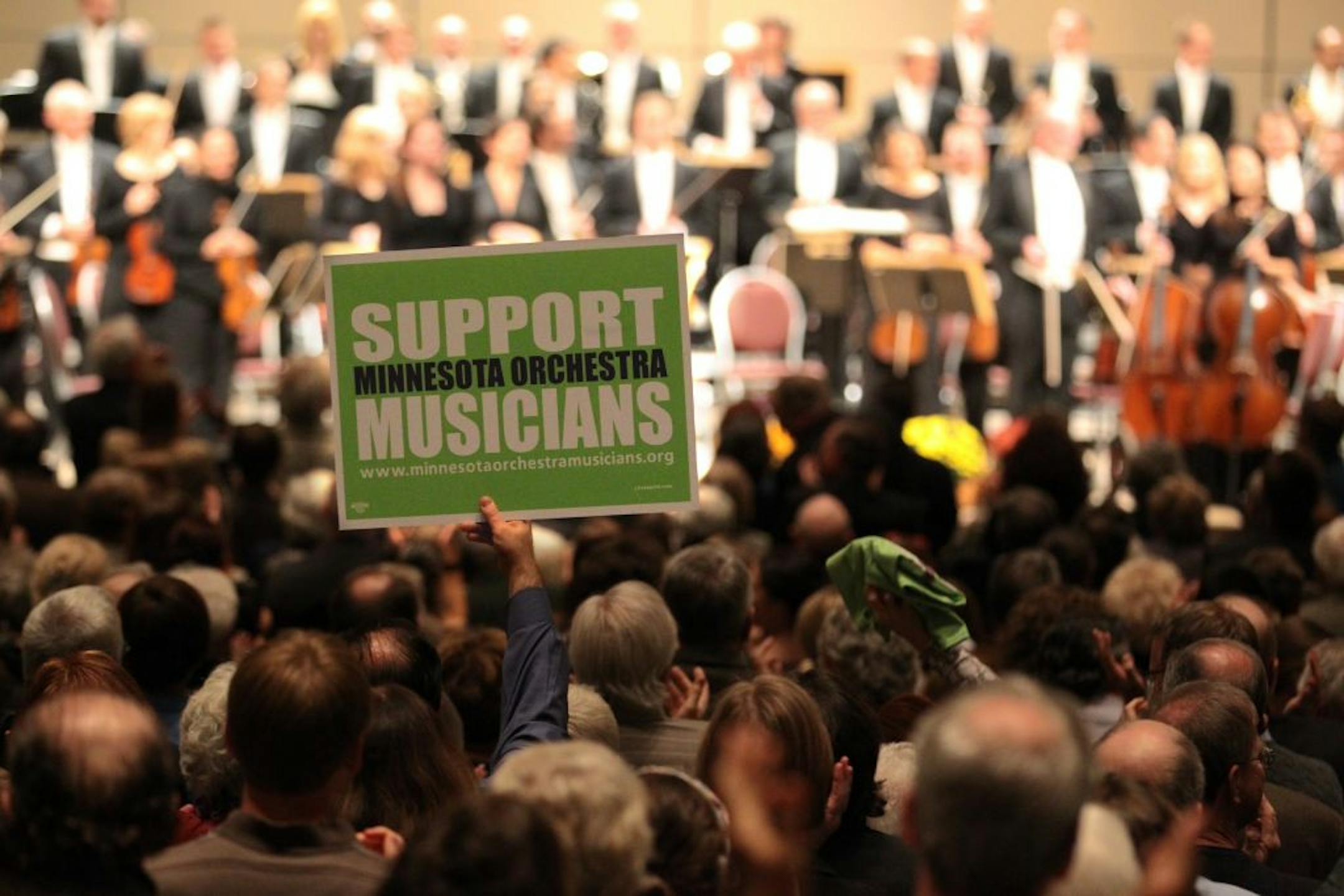 A packed audience gave a standing ovation, and held up a sign in support, to the musicians of the Minnesota orchestra as they took the stage. The players of the Minnesota Orchestra, who are in lock-out over their contract, held a concert the Minneapolis Convention Center on Thursday, October 18, 2012 in Minneapolis, Minn.