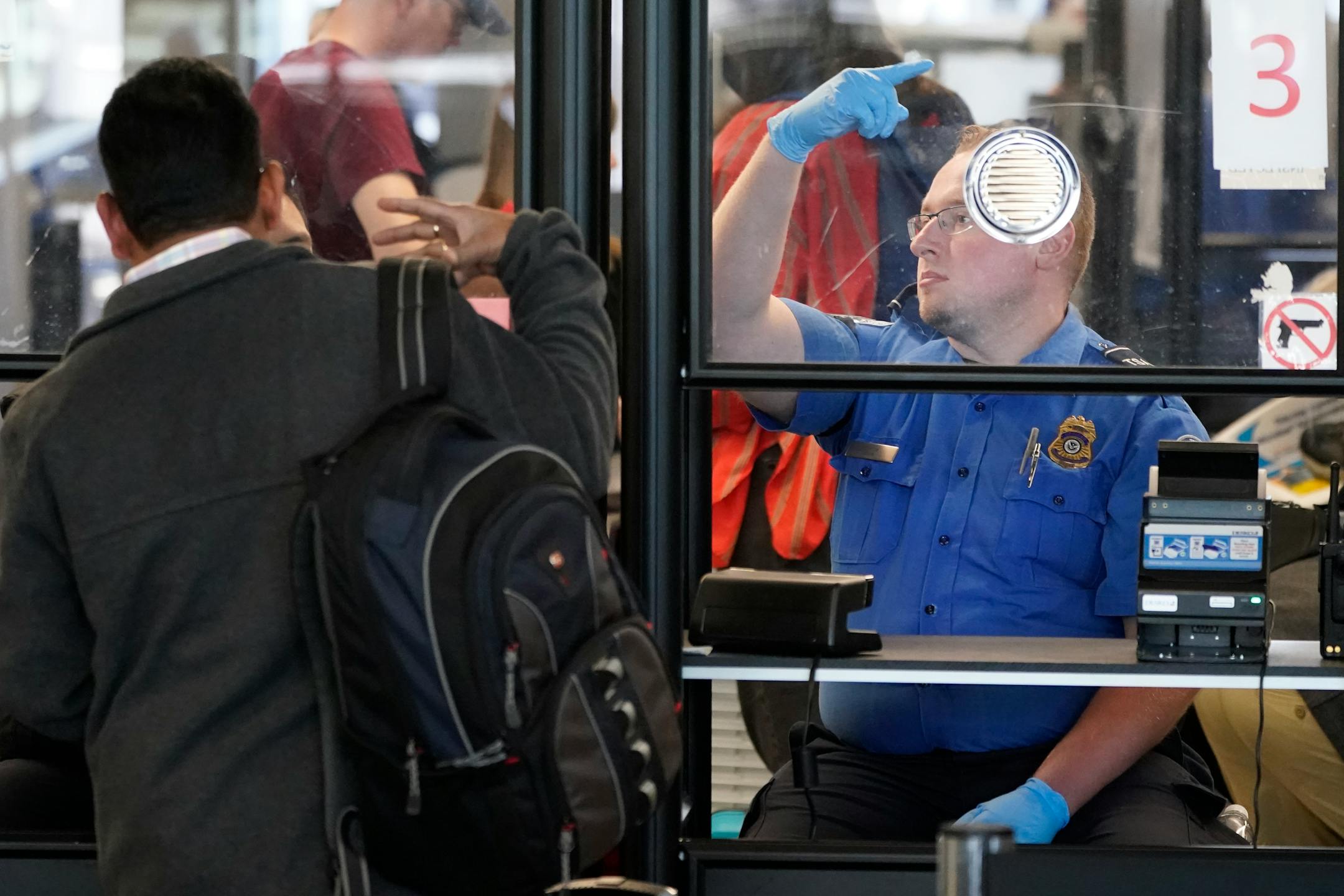 A TSA agent signals for the next airline passenger in line at a security checkpoint in Chicago's O'Hare International Airport Friday, May 26, 2023. (AP Photo/Charles Rex Arbogast)