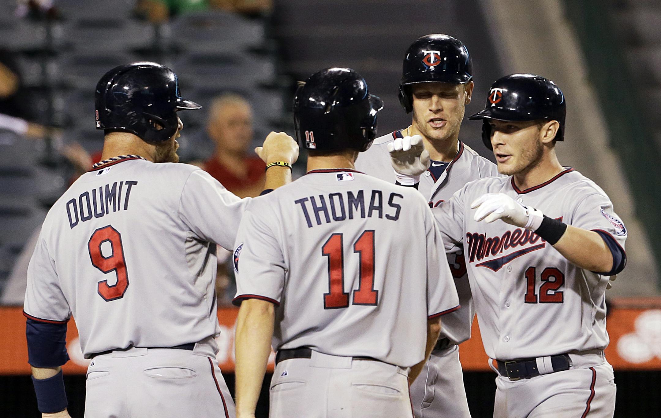 Minnesota Twins, from left, Ryan Doumit, Clete Thomas, and Justin Mourneau congratulate Chris Hermann (12) as all score on Hermann's grands slam home run against the Los Angeles Angels in the 10th inning of a baseball game in Anaheim, Calif., Tuesday, July 23, 2013. (AP Photo/Reed Saxon)