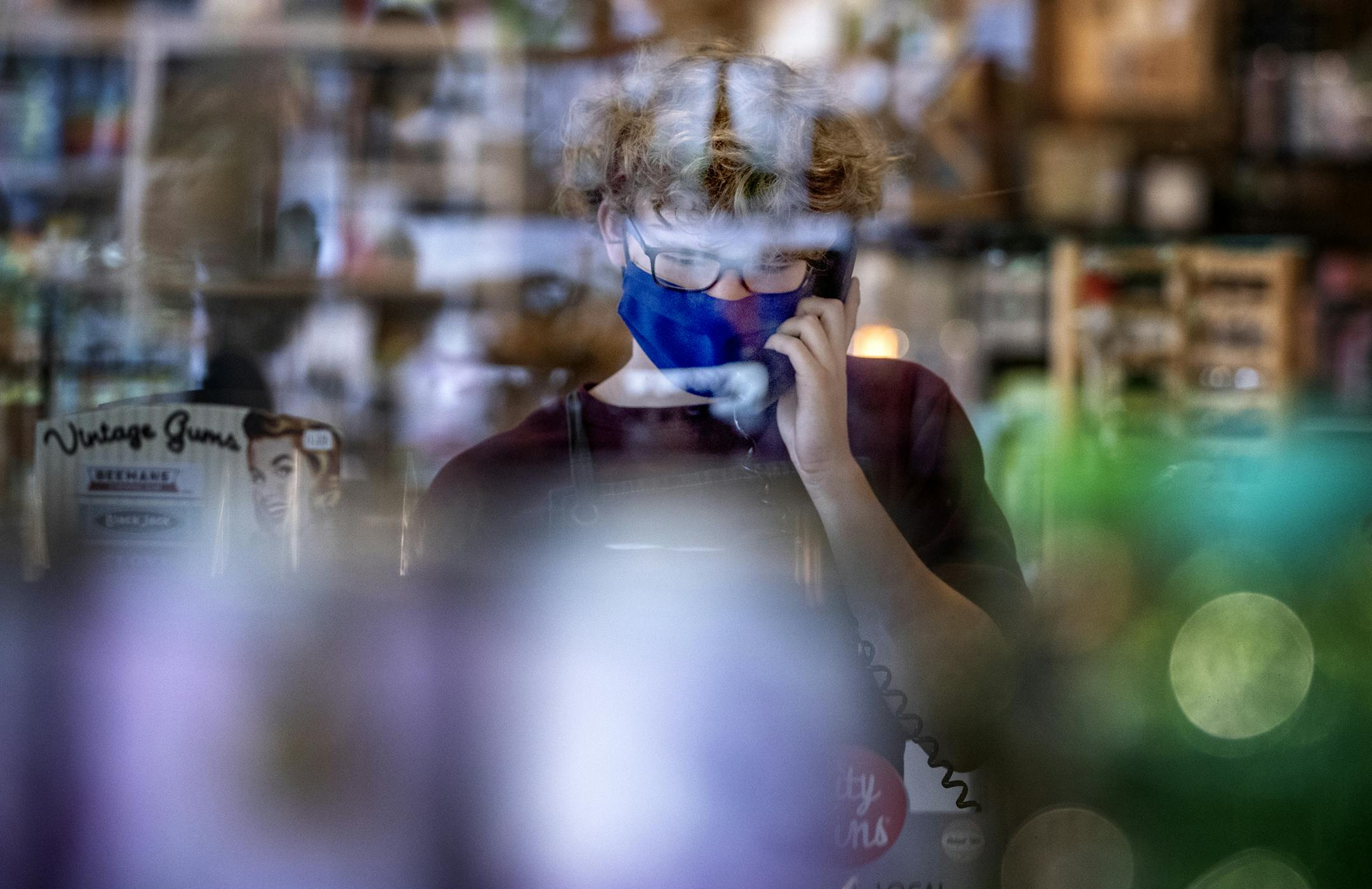 Andrew Hall answered a phone call behind a plastic screen at the counter while working at Patina in Minneapolis. ] CARLOS GONZALEZ • cgonzalez@startribune.com - Minneapolis, MN – May 18, 2020, COVID-19, Coronavirus, Patina before, during opening day and first week reopen.