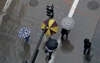 Seen from above at the corner of S. 6th St. and 2nd Avenue S. umbrella-protected commuters cross the street Wednesday, April 26, 2017, in downtown Min