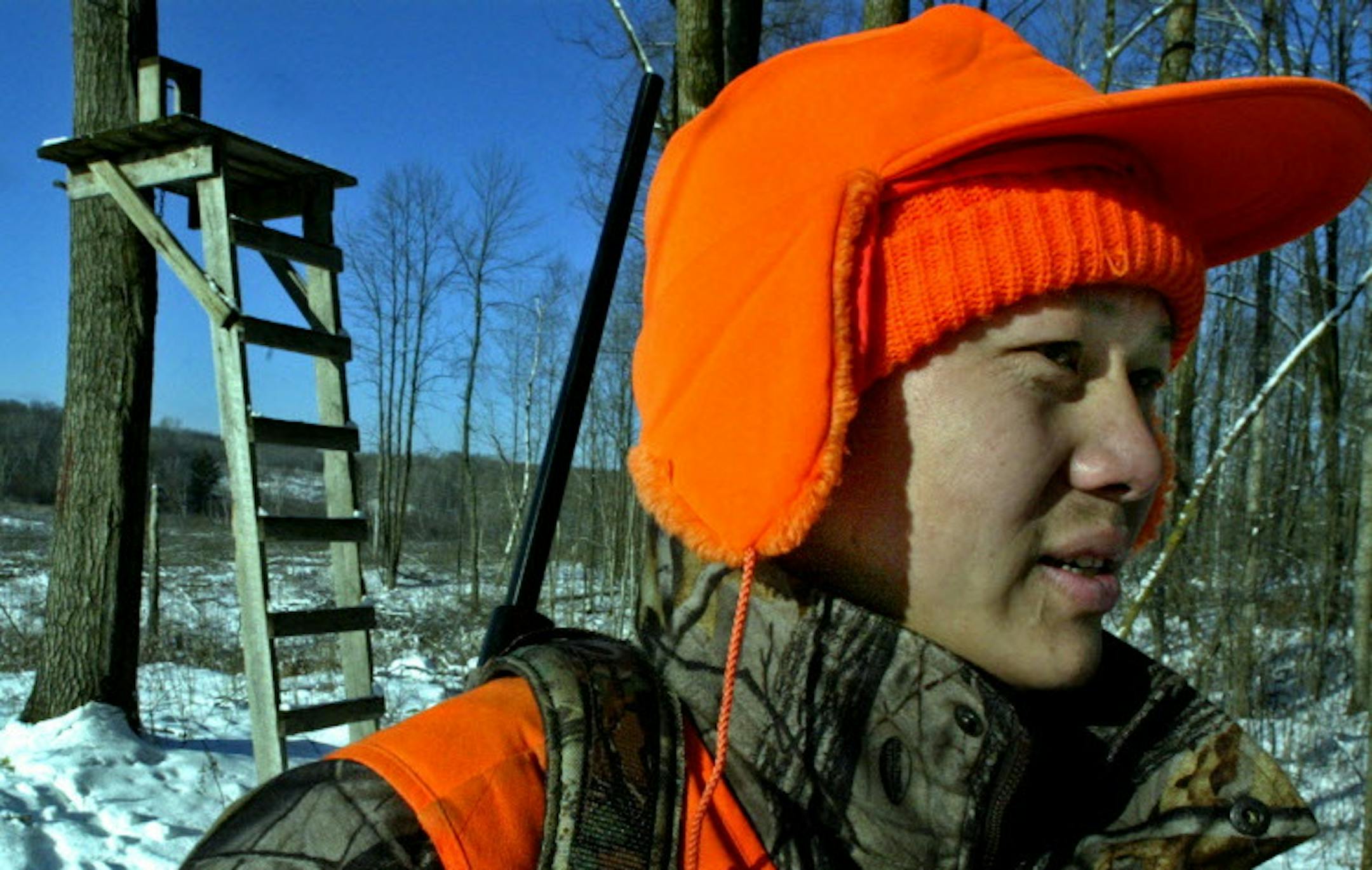 Marlin Levison - Strib 11/28/04 - Assign #- We tagg along with Hmong deer hunters Kao Xiong and Jeo Bee Xiong, both of Eau Claire WI, as they hunt for deer from tree stands in the woods of northwest Wisconsin - the area a Hmong hunter is under investigation for the recent shooting deaths of six Caucasian hunters. IN THIS PHOTO: Kao Xiong leaves his deer stand in background. ORG XMIT: MIN2017010613321423
