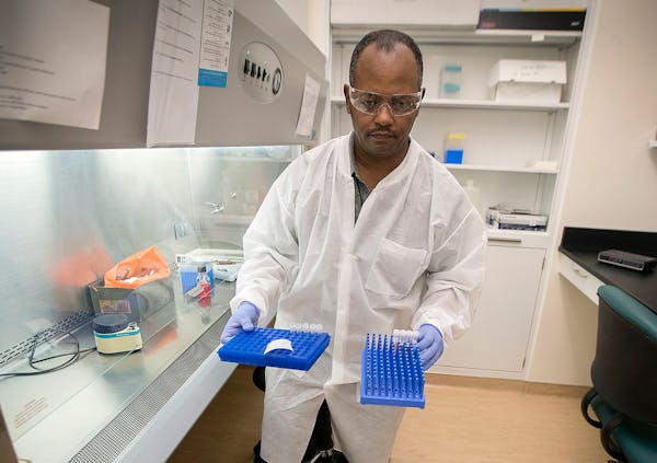 Netsanet Bekele, cq, a clinical lab scientist for the Minnesota Health Department test for measles as he places the tubes into a robot, Thursday, May 