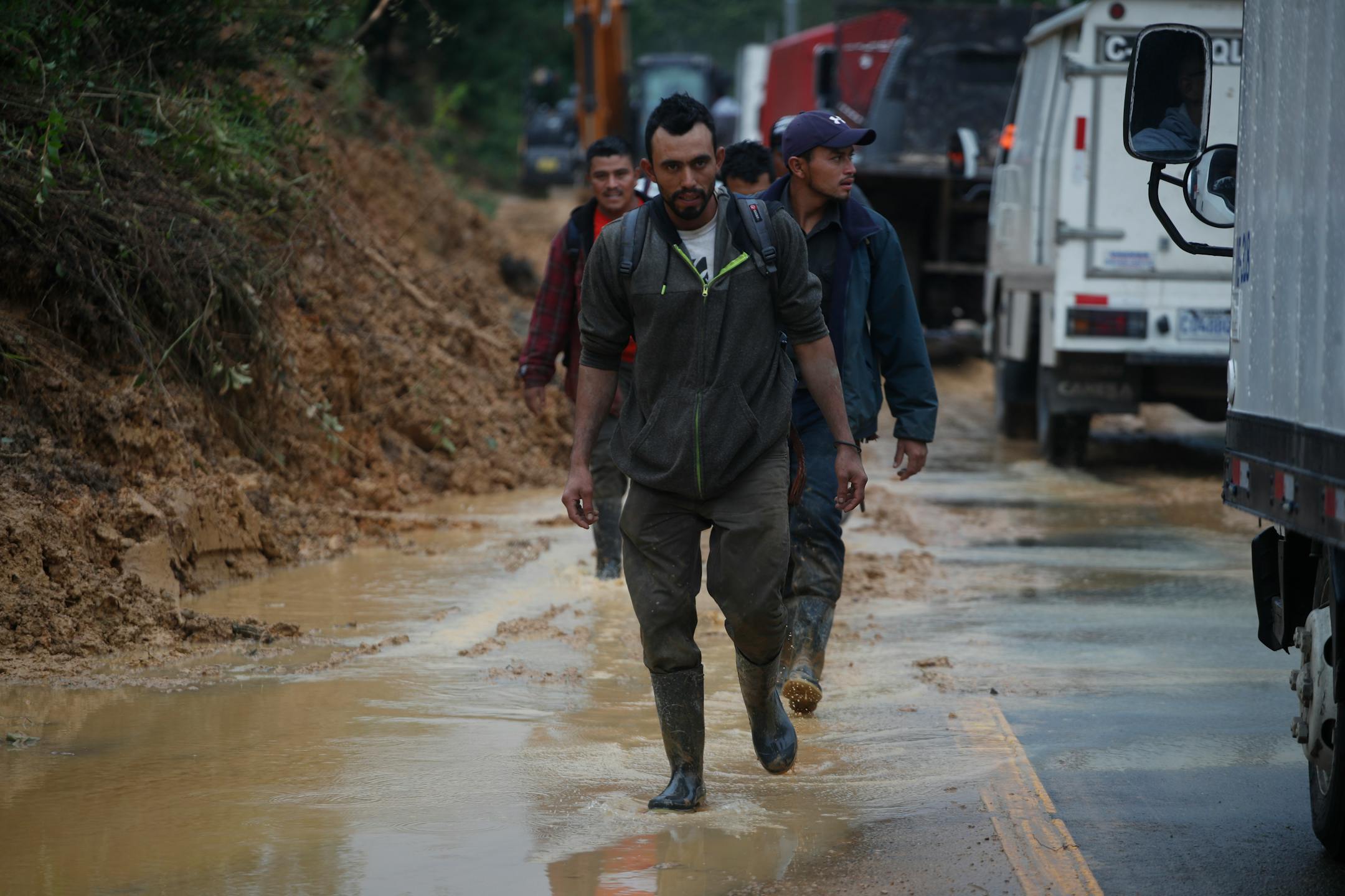 Residents walk on a road blocking traffic with debris brought on by a landslide in the aftermath of Hurricane Eta, in Purulha, northern Guatemala on Friday. As the remnants of Eta moved back over Caribbean waters, governments in Central America worked to tally the displaced and dead, and recover bodies from landslides and flooding that claimed dozens of lives from Guatemala to Panama.