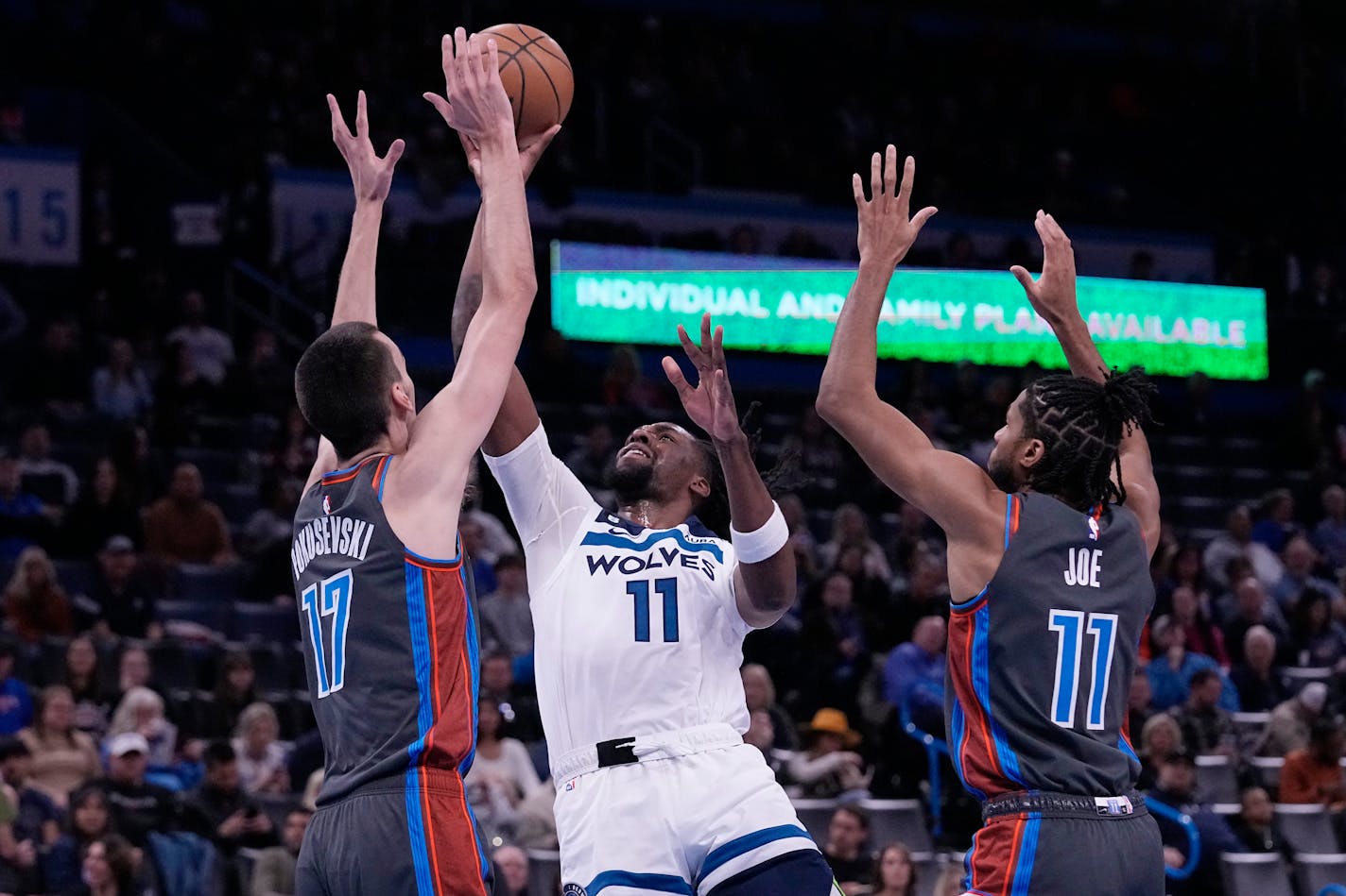 Minnesota Timberwolves center Naz Reid (11) shoots between Oklahoma City Thunder forward Aleksej Pokusevski (17) and guard Isaiah Joe (11) in the first half of an NBA basketball game Friday, Dec. 16, 2022, in Oklahoma City. (AP Photo/Sue Ogrocki)