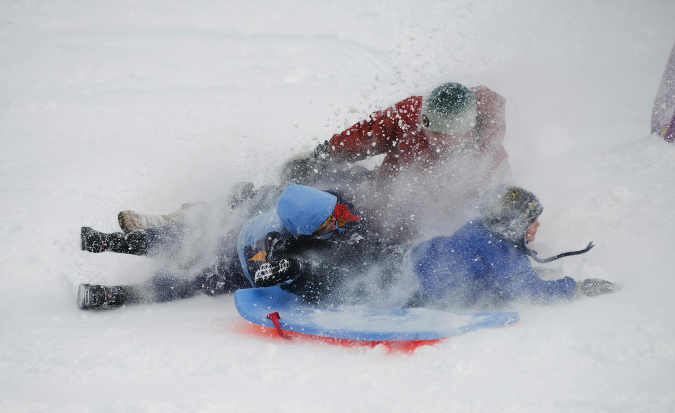 Ben Danielson, his son Cooper Danielson, 6, and Cooper's friend Sam Zelazo, 6, ended their sledding run down a hill at St.Paul's Highland Park in a cloud of snow after hitting some bumps half way down.