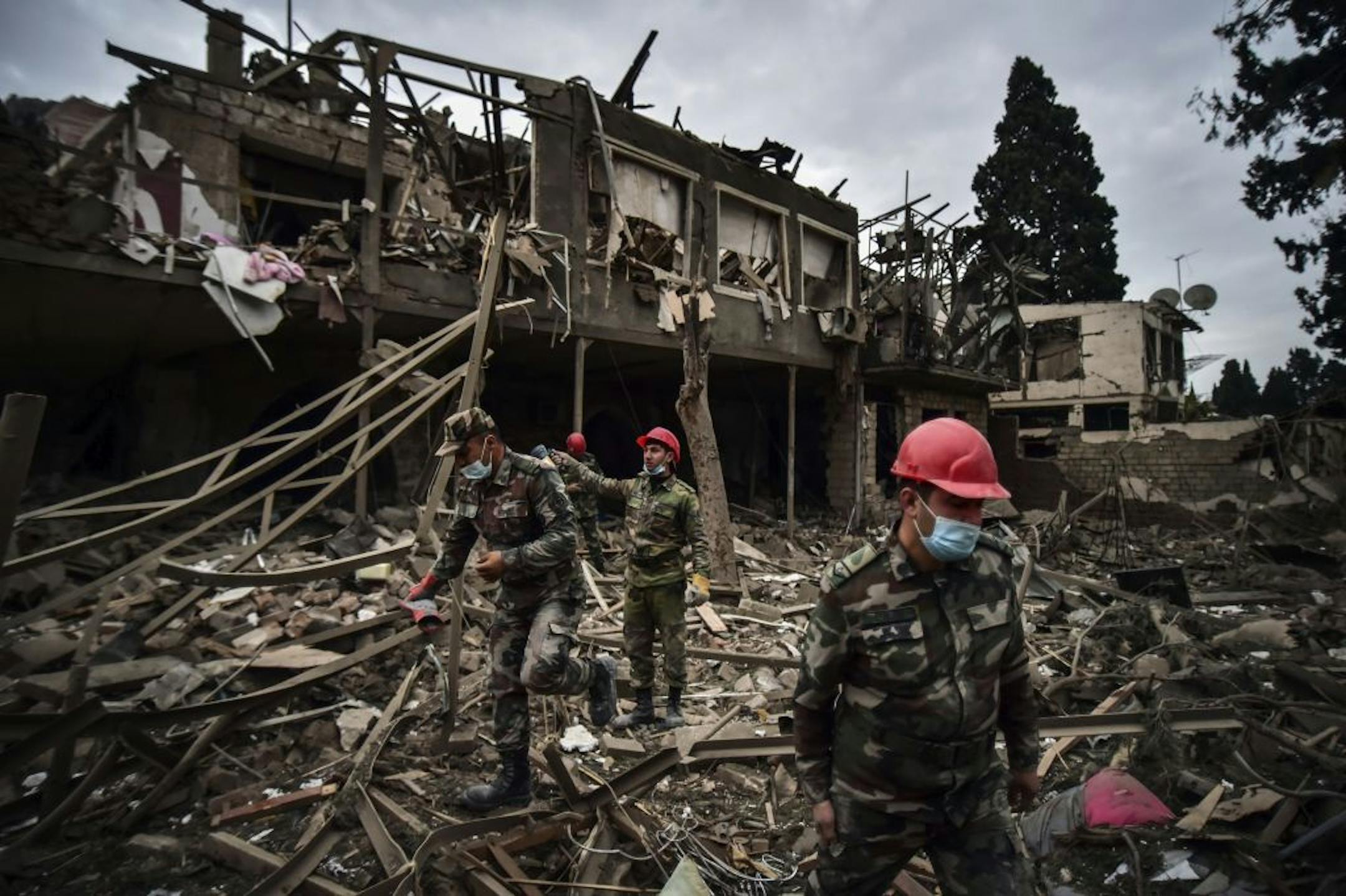 Azerbaijani soldiers and firefighters search for survivors after rocket fire overnight by Armenian forces, early Sunday, Oct. 11, 2020, in a residential area in Ganja, Azerbaijan's second largest city, near the border with Armenia. Several civilians were killed and dozens were wounded. Russian President Vladimir Putin brokered a cease-fire on Friday in a series of calls with President Ilham Aliyev of Azerbaijan and Armenia's Prime Minister Nikol Pashinian.