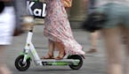 In this Tuesday, Aug. 6, 2019 photo a woman drives an electric scooter on a square in front of the Brandenburg Gate in Berlin, Germany. (AP Photo/Mich