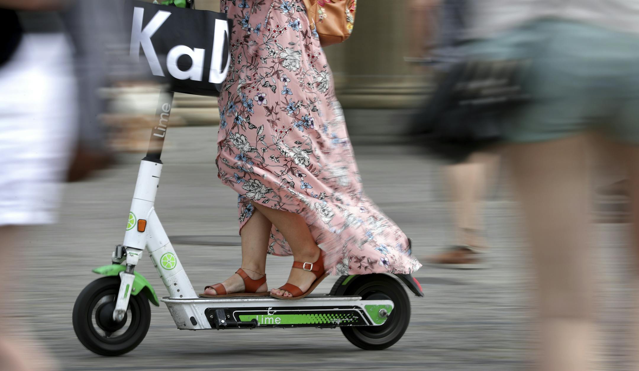 In this Tuesday, Aug. 6, 2019 photo a woman drives an electric scooter on a square in front of the Brandenburg Gate in Berlin, Germany. (AP Photo/Michael Sohn)