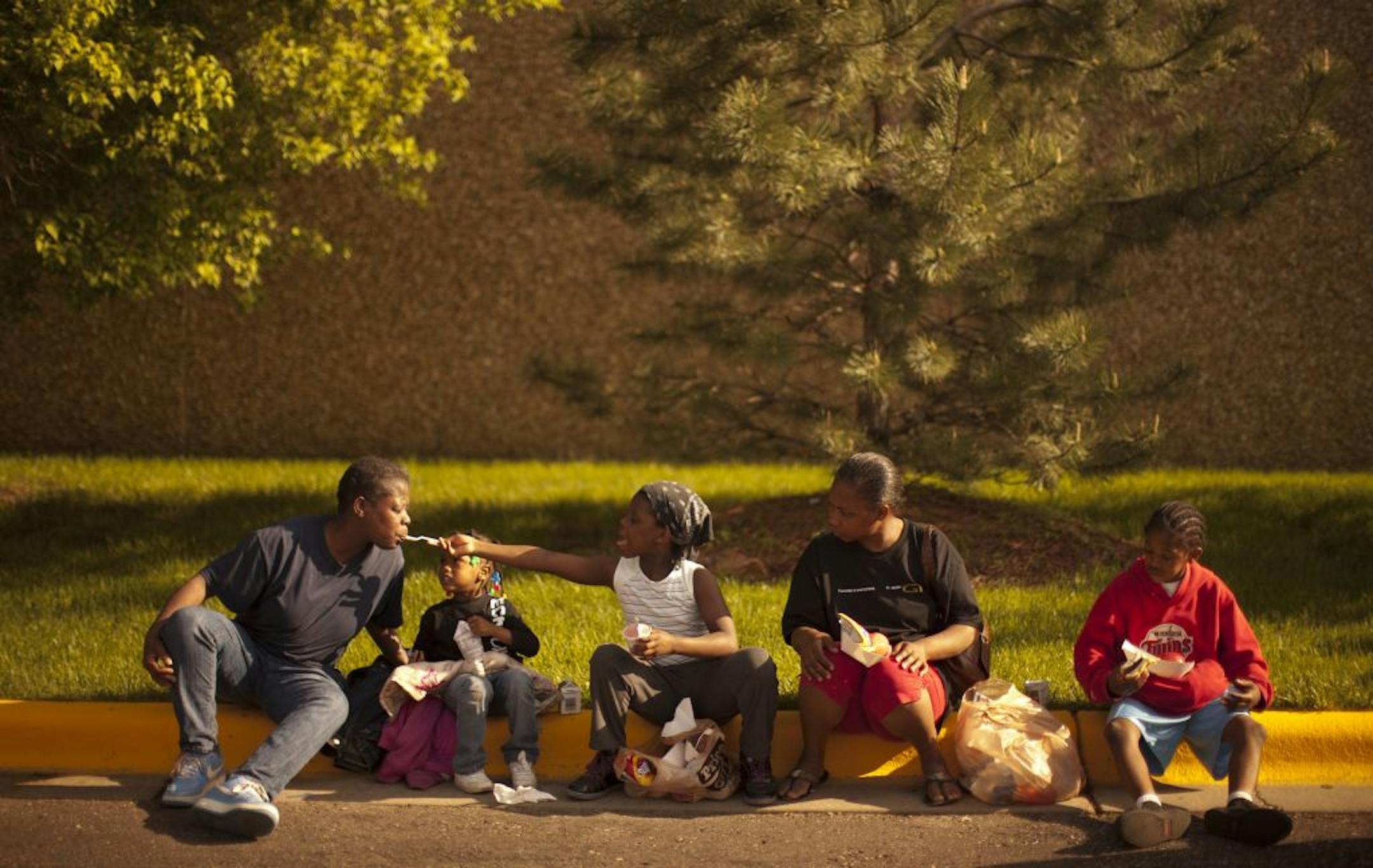 Diane Peaches got a taste of yogurt from daughter Aaliyha, 7, as they ate dinner provided by Cub Foods Monday night in the parking lot. Between them was Shamajai Mydens, 3. At right were Latricia Dortch and Brian Booth, 10.