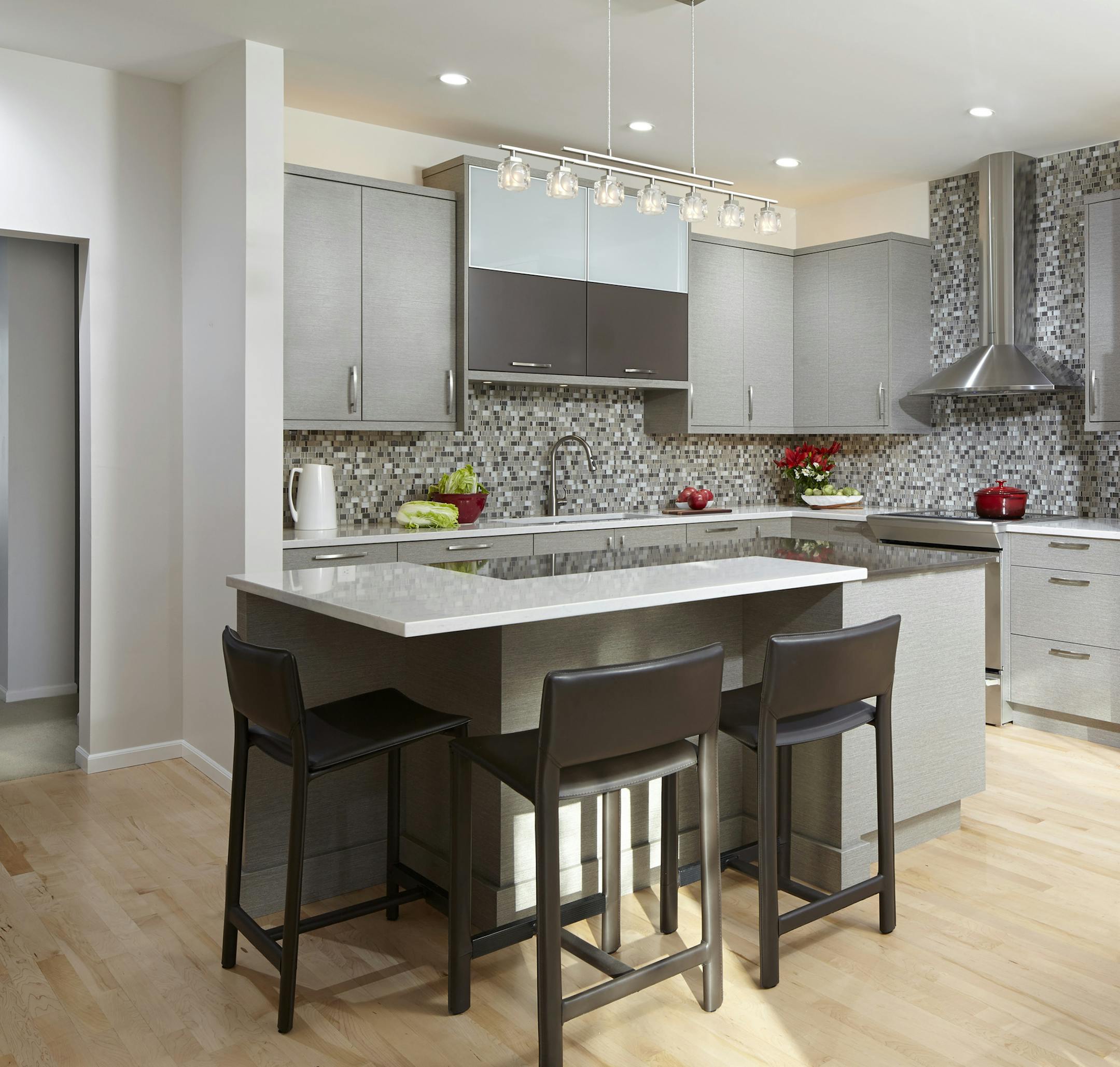The glass and stone mosaic backsplash echoes the shades in the cabinets throughout the cooking and entertaining area.