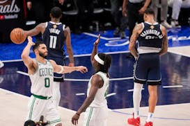 Boston Celtics forward Jayson Tatum (0) and guard Jrue Holiday react as Dallas Mavericks guard Kyrie Irving (11) and forward P.J. Washington walk off 