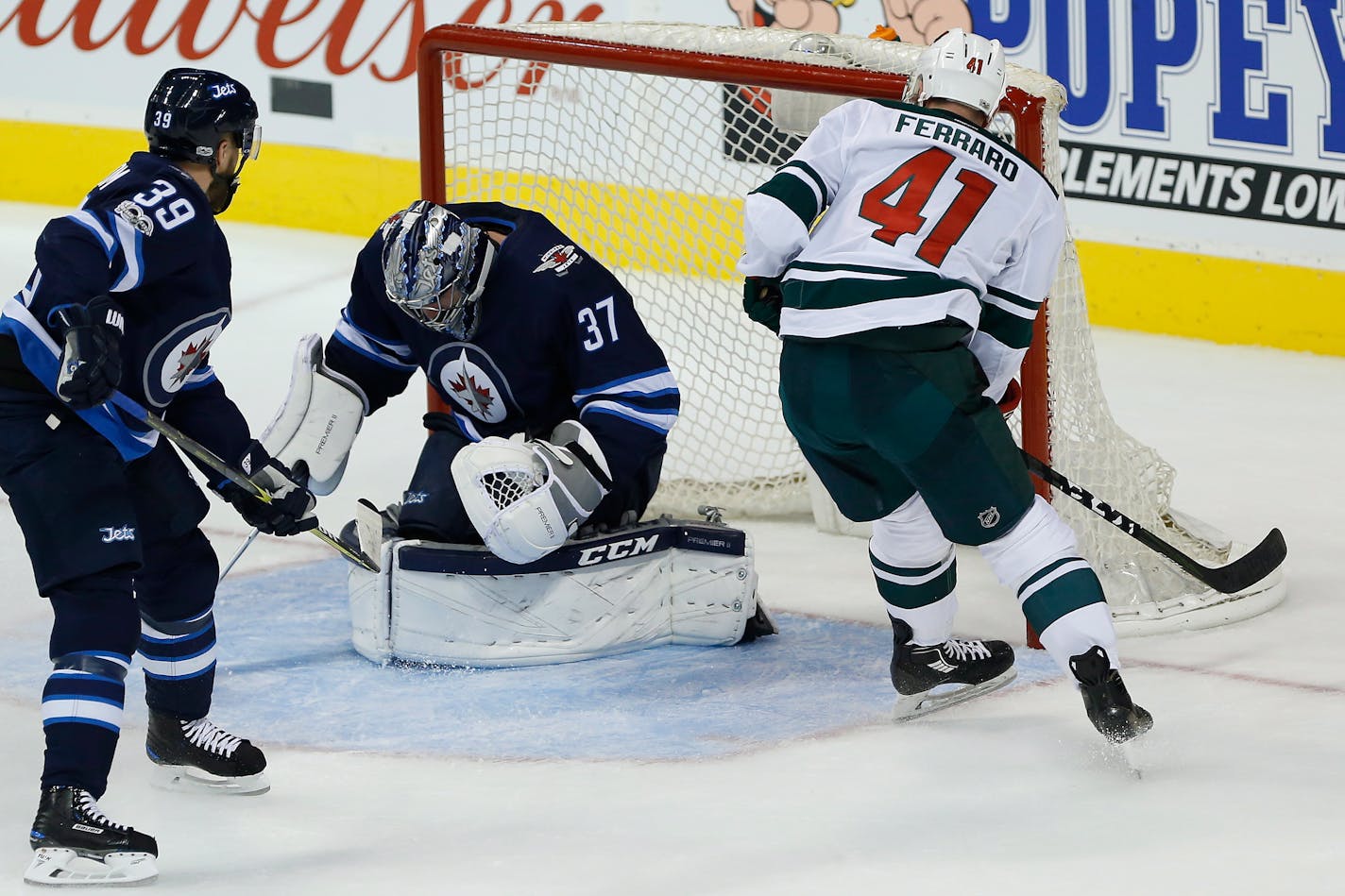 Winnipeg Jets goaltender Connor Hellebuyck (37) stops Minnesota Wild's Landon Ferraro's (41) breakaway attempt as Toby Enstrom (39) defends during the first period of an NHL hockey game Friday, Oct. 20, 2017, in Winnipeg, Manitoba. (John Woods/The Canadian Press via AP)