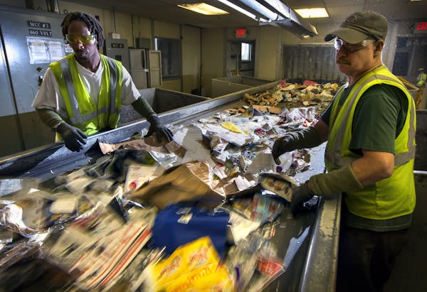 Jerrell Stewart (left) and Martin Kellers (right) work the sort line at Dem-Con recycling facility in Shakopee. ] Global economic trends are putting a