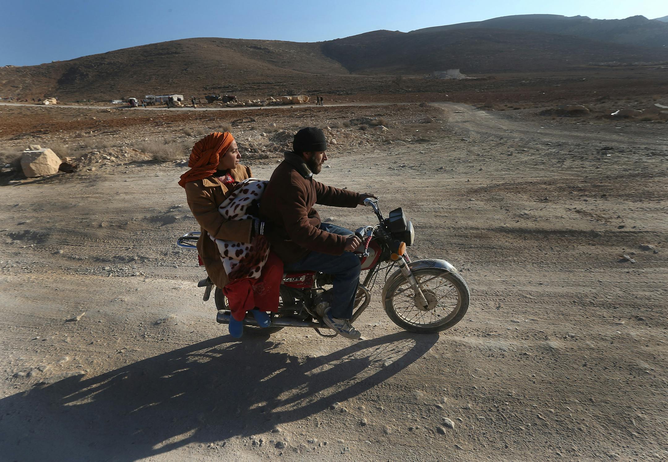 A Syrian man with his wife and child ride a motorcycle as they flee from Yabroud, the last rebel stronghold in Syria's mountainous Qalamoun region, on their way to the Lebanese-Syrian border town of Arssal, in eastern Lebanon, Wednesday, Feb. 12, 2014. In Lebanon, preparations were underway to receive more Syrians fleeing the area. Syrian warplanes pounded a rebel-held town near the Lebanese border on Wednesday, activists said, as opposition leaders in Geneva called on Russia to put pressure on