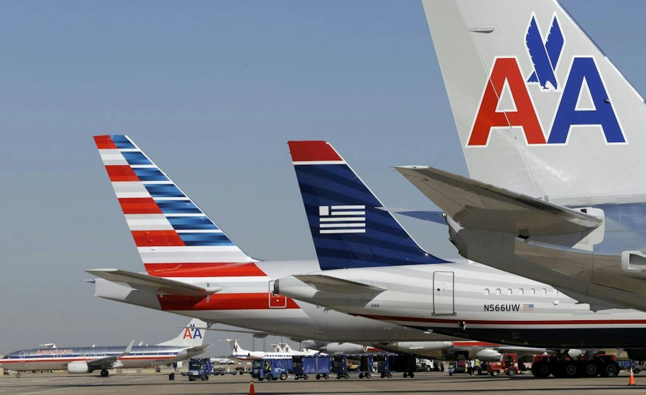 FILE - In this Thursday, Feb. 14, 2013 file photo, U.S. Airways and American Airlines planes are shown at gates at DFW International Airport in Grapevine, Texas.